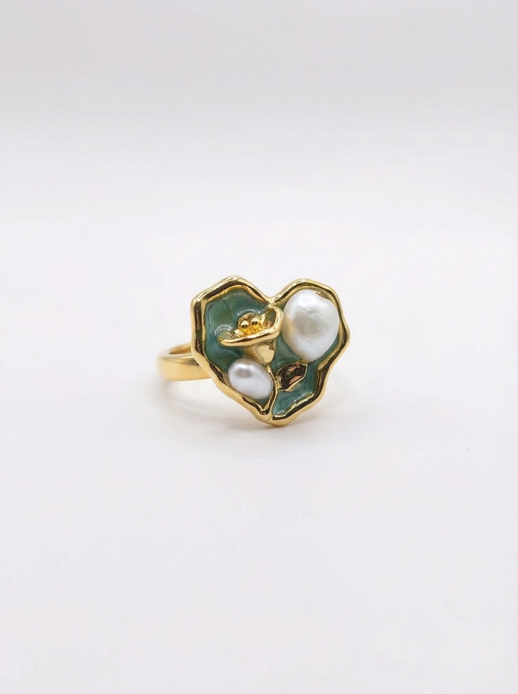 Gold ring with green enamel and pearl on a white background