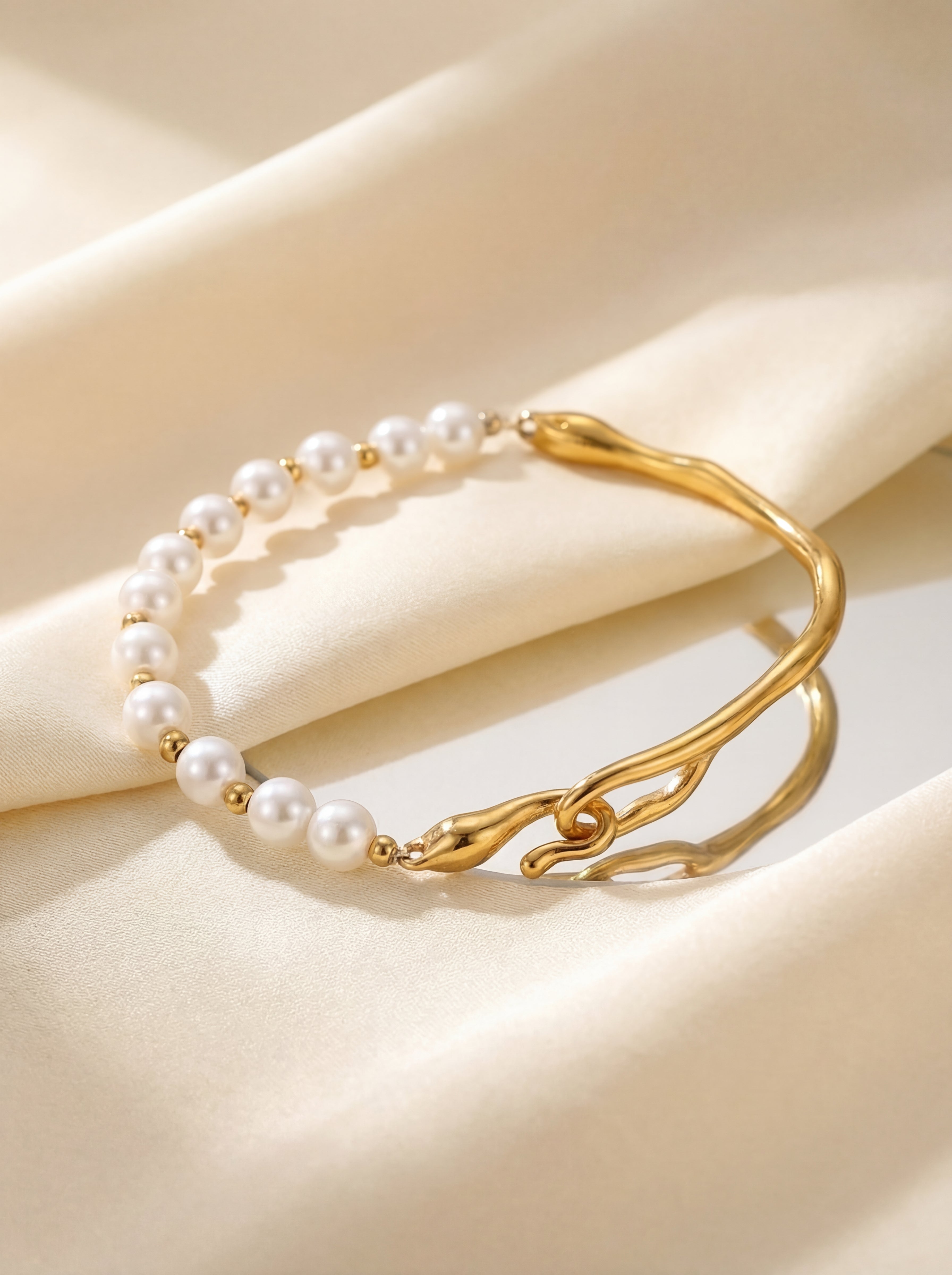 Gold bracelet with pearl beads on a beige fabric background