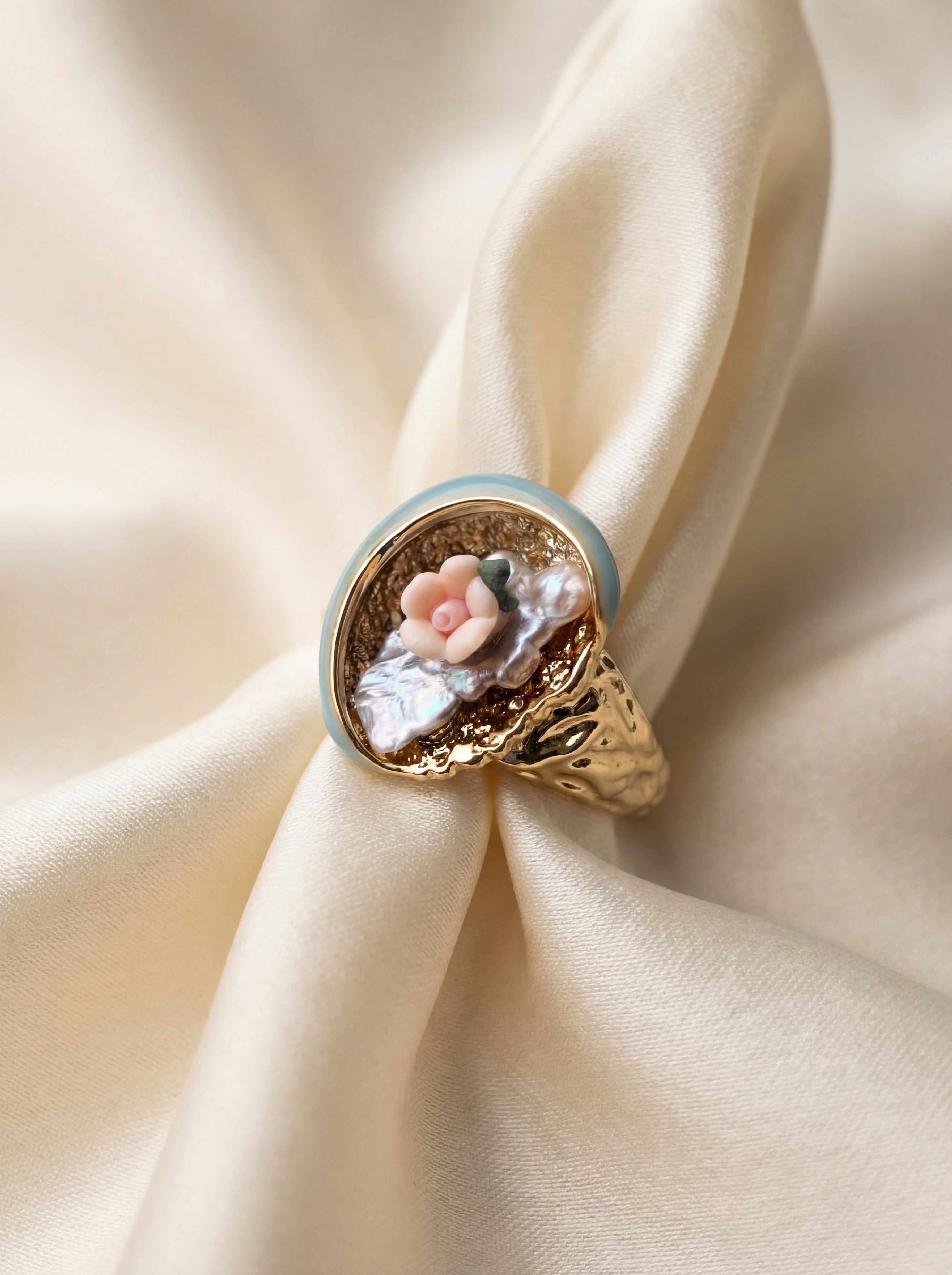 Gold ring with floral design on a beige fabric background