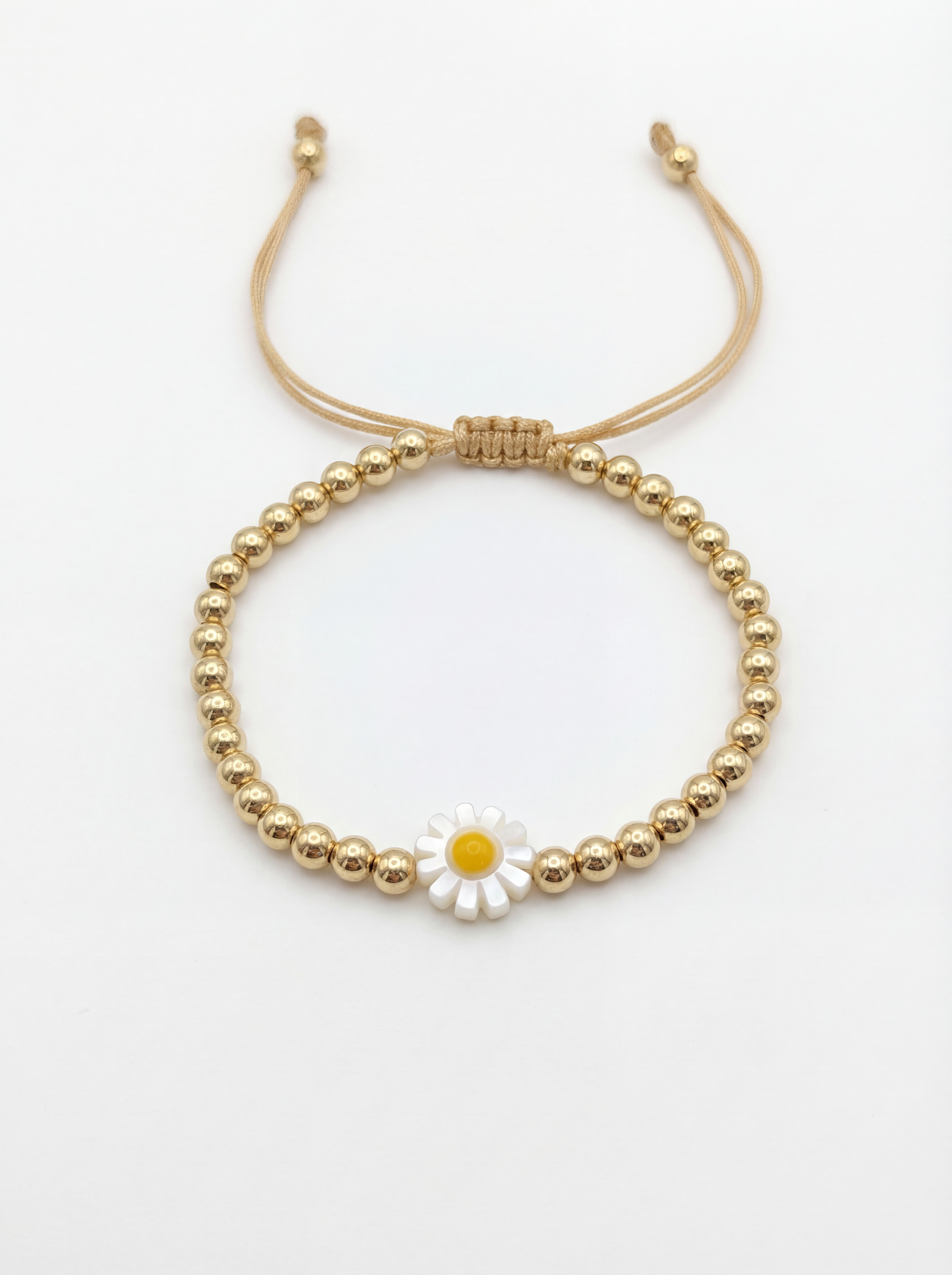 Gold beaded bracelet with a daisy charm on a white background