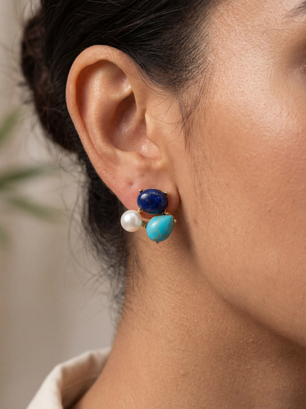 Close-up of an ear wearing a blue and pearl earring with a blurred background