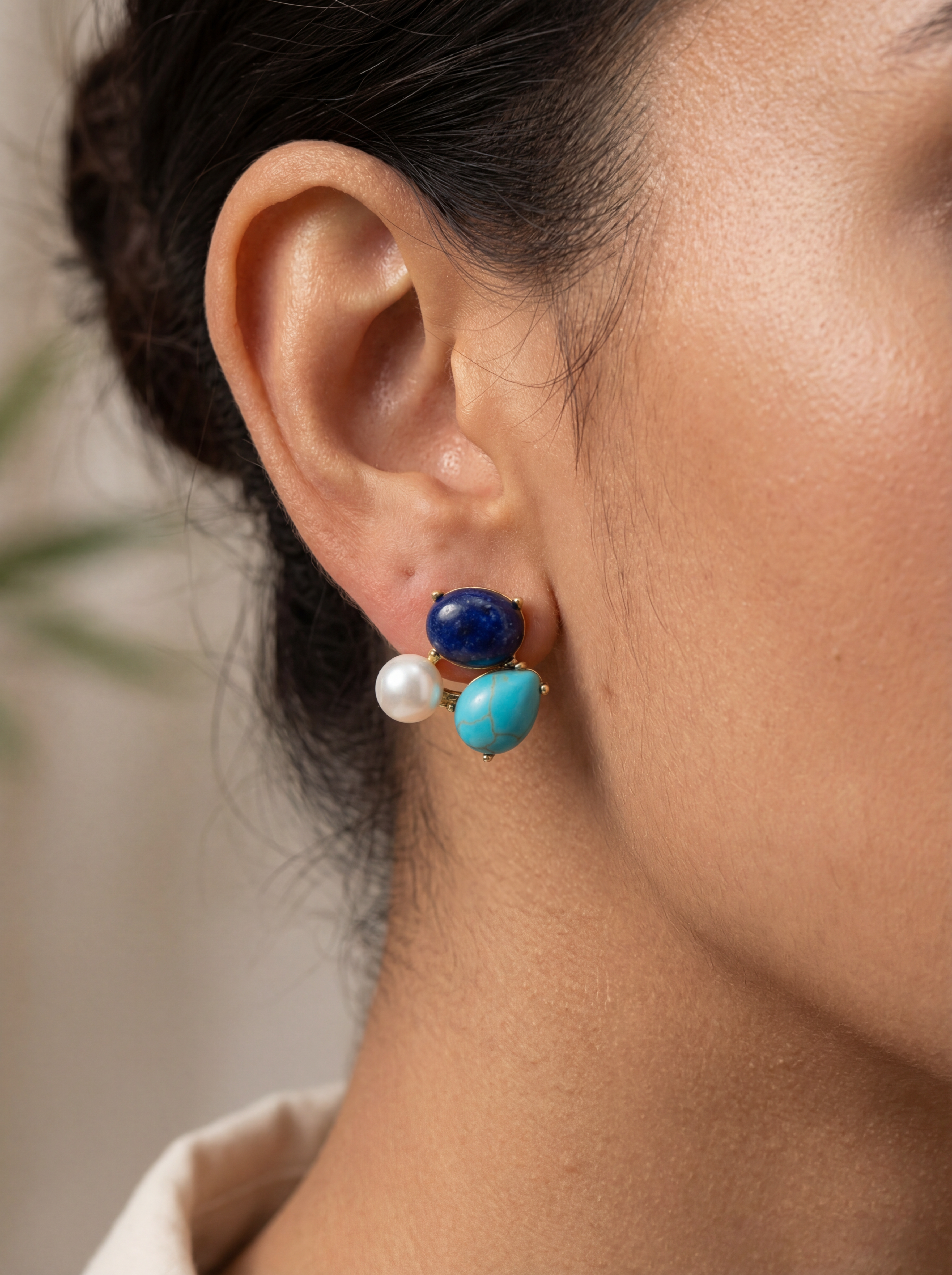 Close-up of an ear wearing a blue and pearl earring with a blurred background