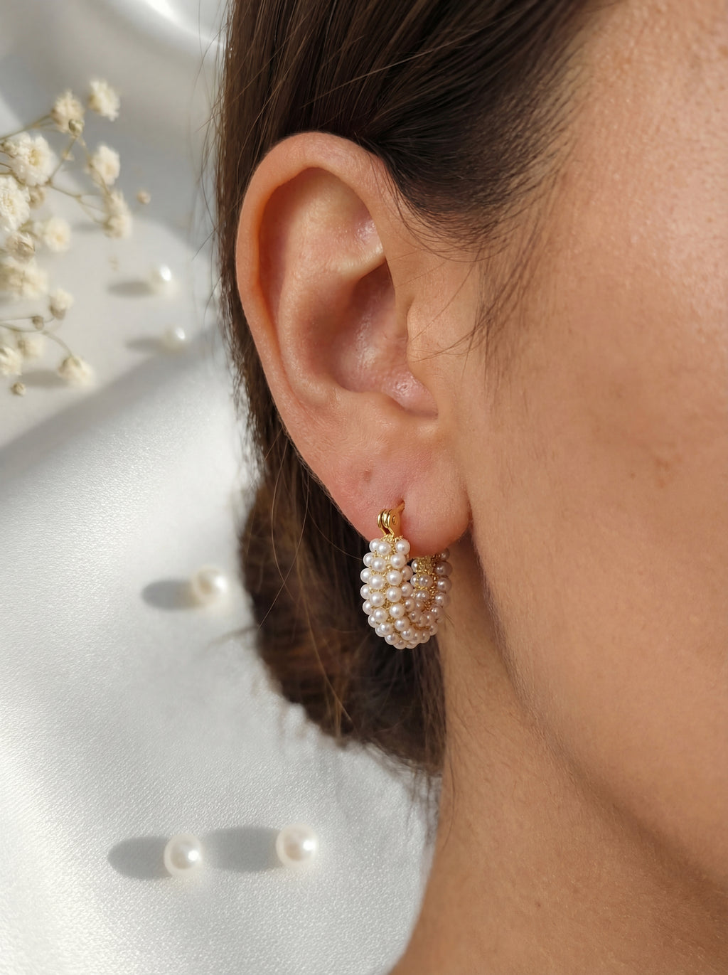 Pearl earrings worn by a person with a neutral background