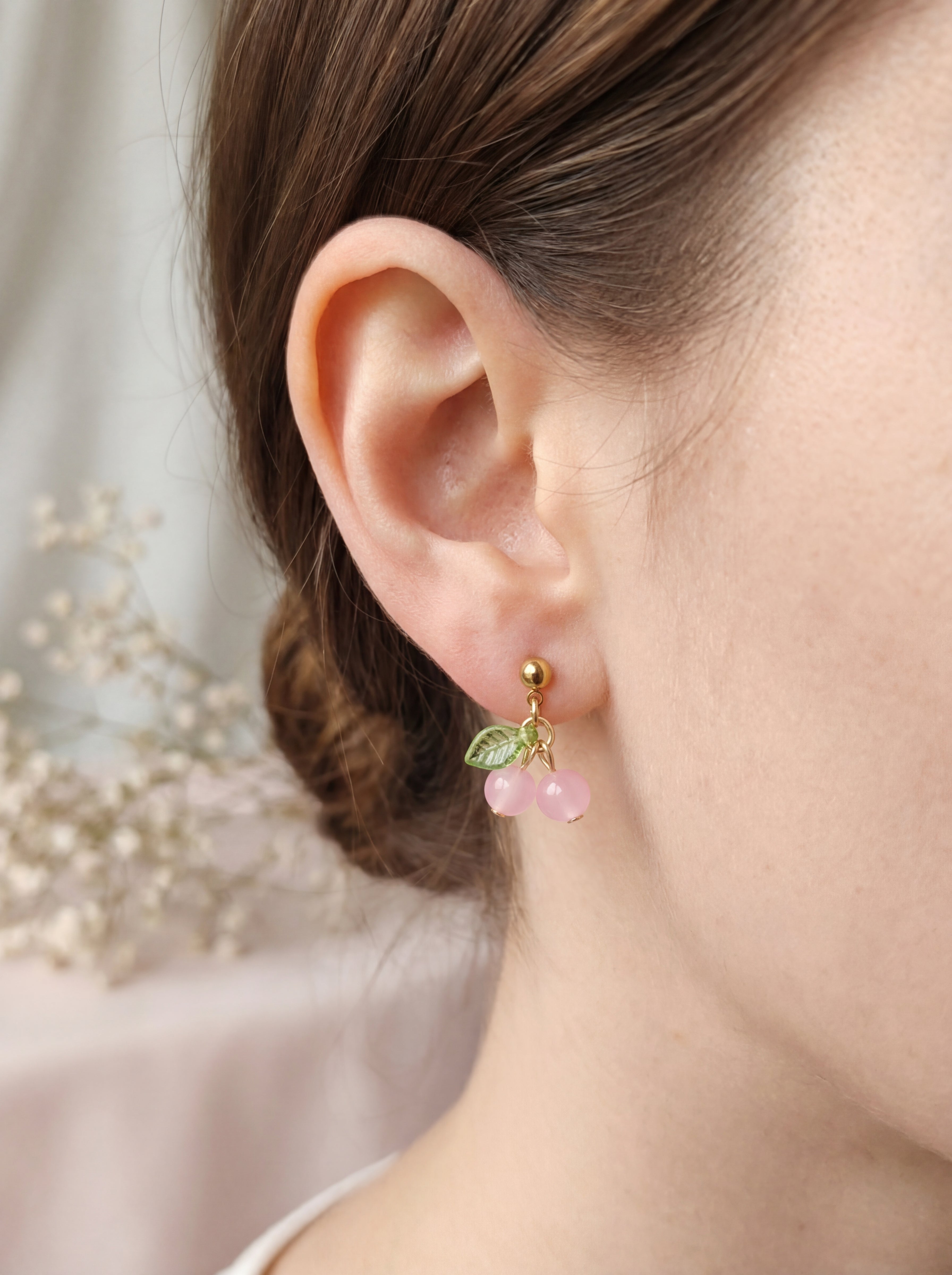 Close-up of an ear wearing a pink floral earring with a blurred background
