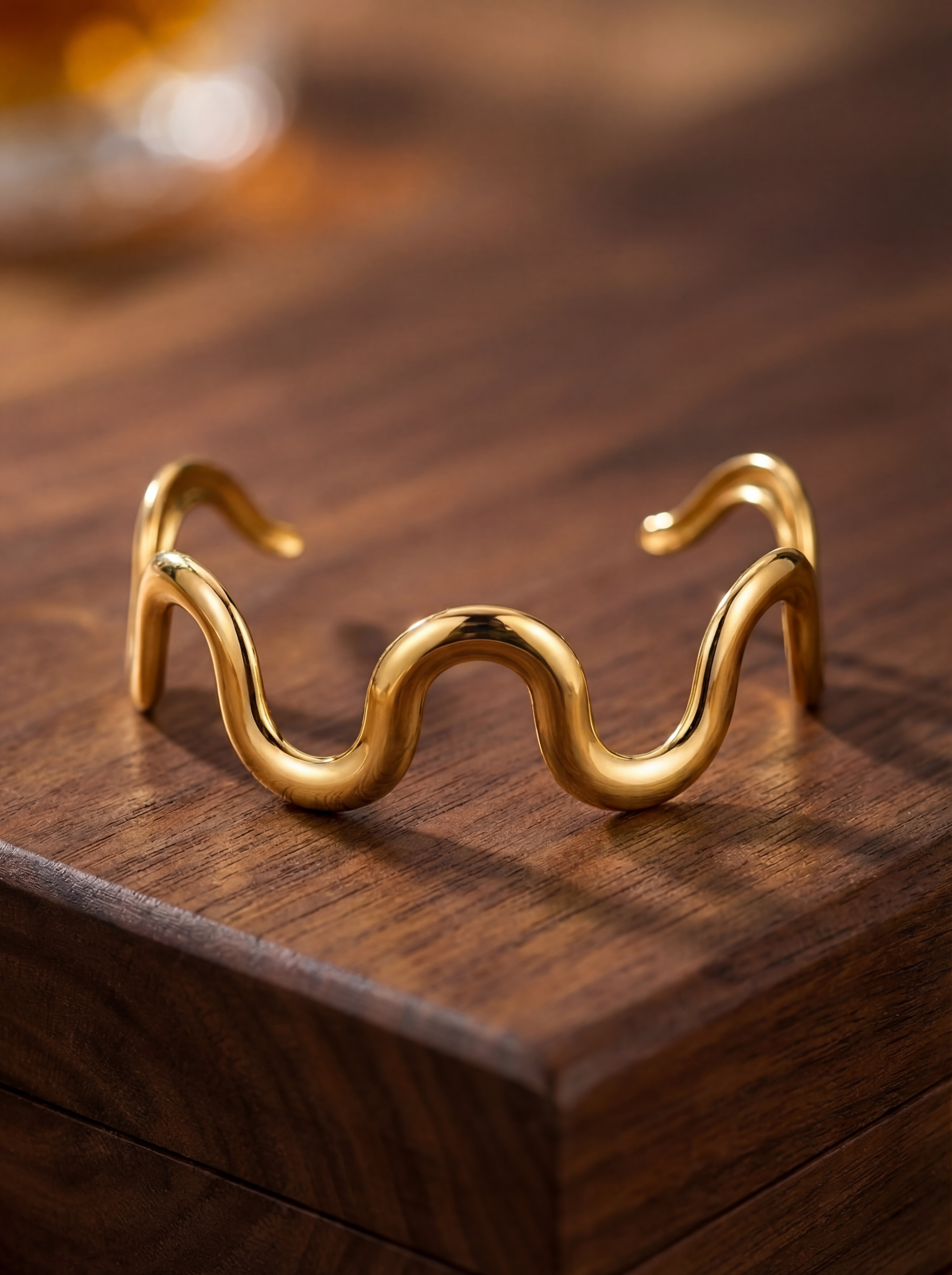 Gold wavy bracelet on a wooden surface
