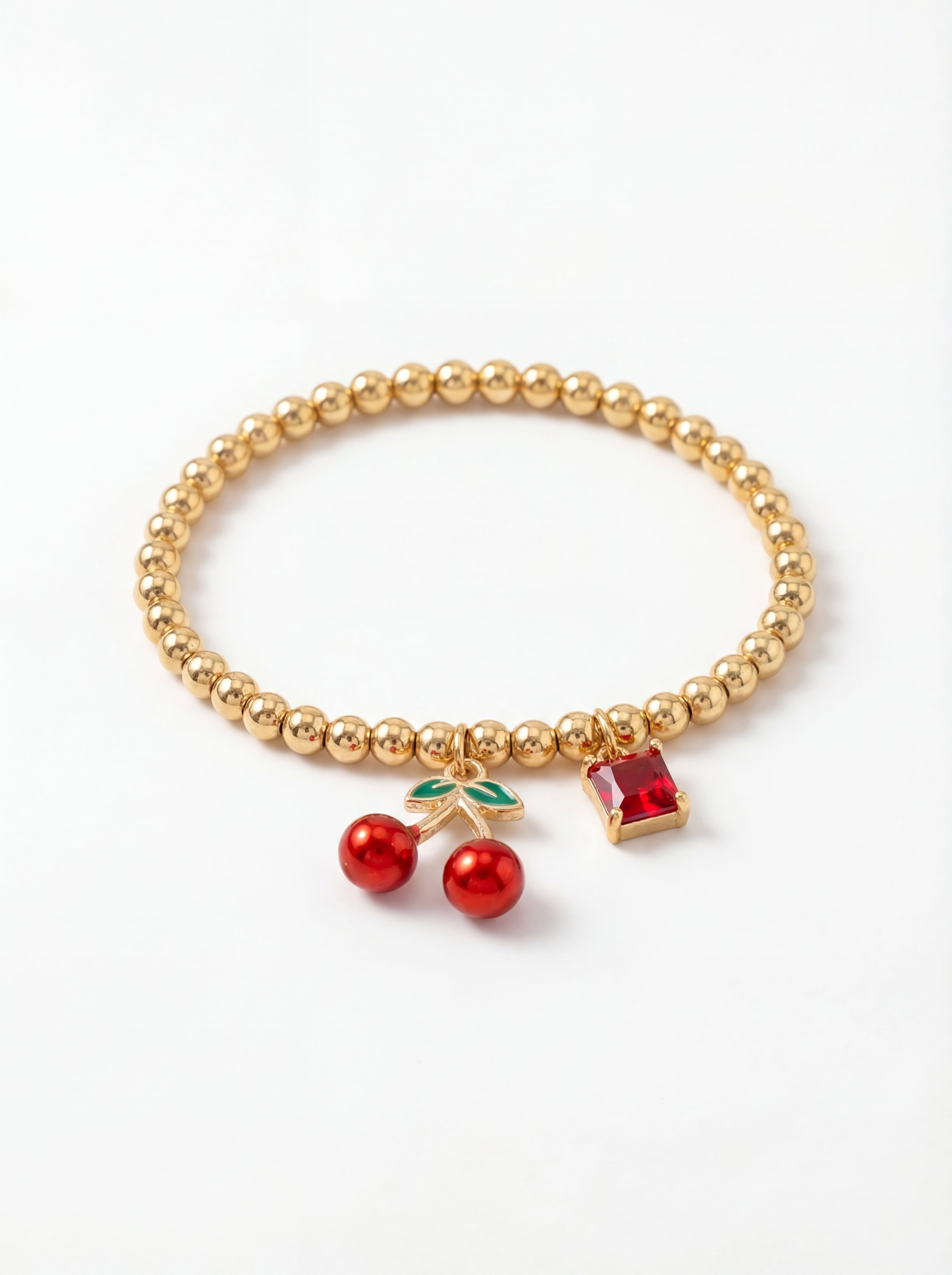 Gold beaded bracelet with cherry and gemstone charms on a white background