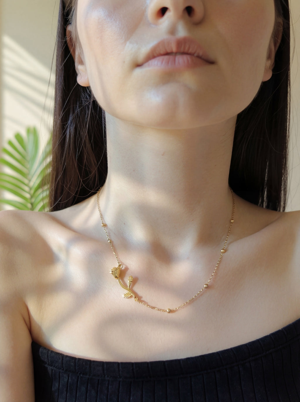 Close-up of a person wearing a delicate gold necklace with a blurred background