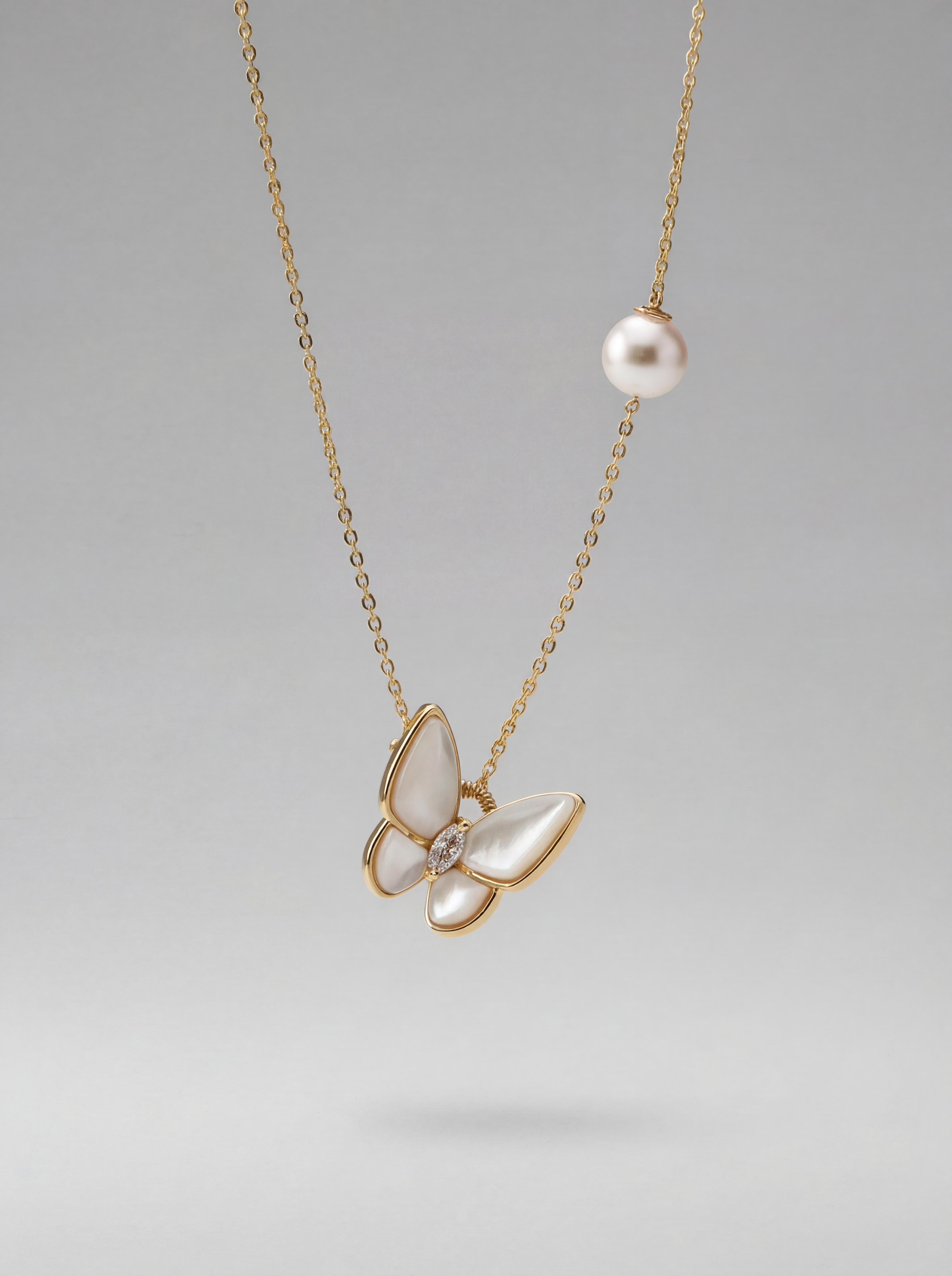 Butterfly-shaped pendant necklace with pearl and gemstone details on a gray background