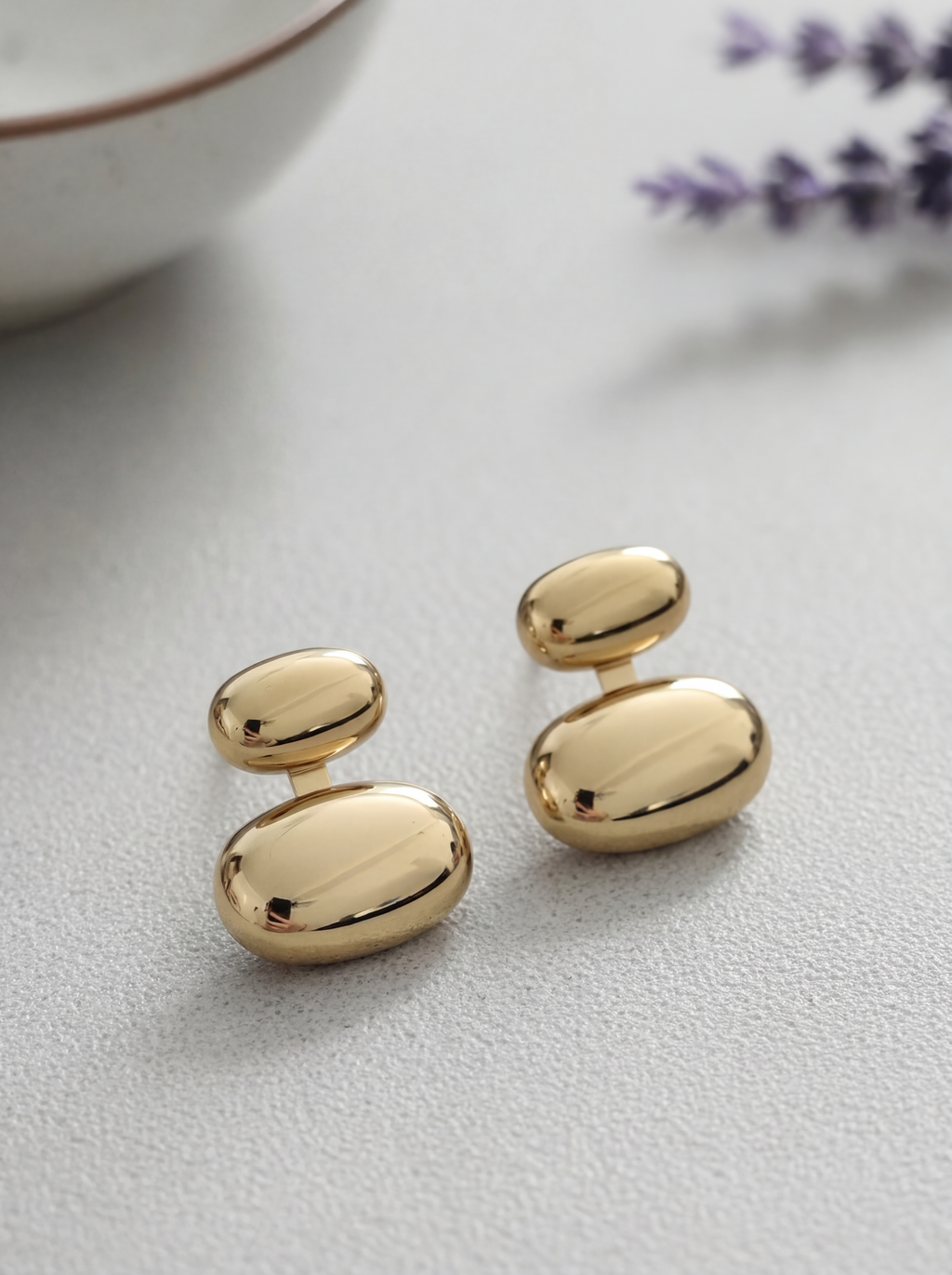 Gold earrings on a light gray surface with a blurred background