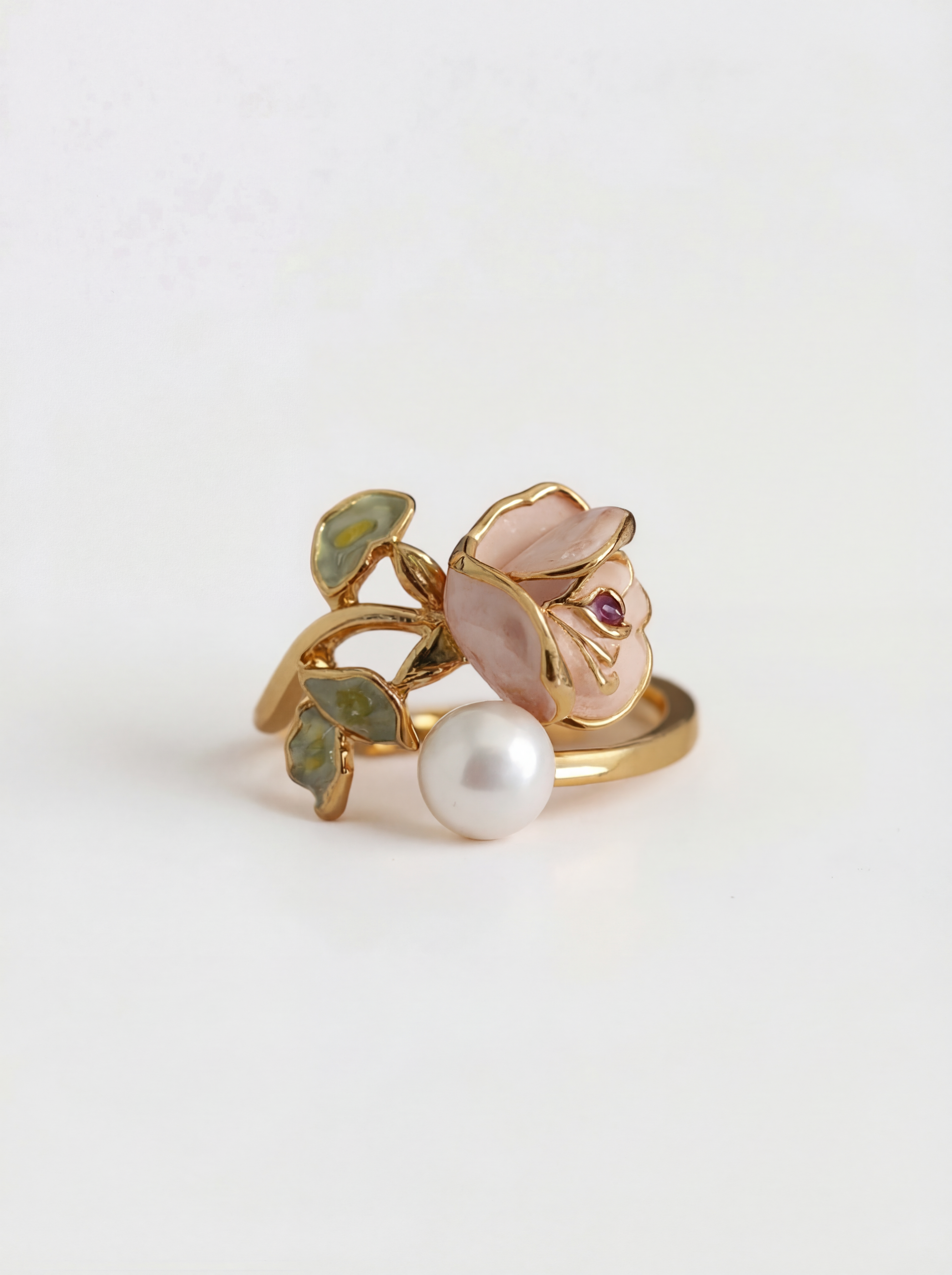Gold ring with a pearl and gemstone on a light gray background