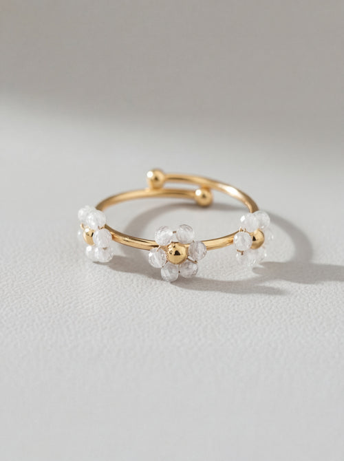 Gold ring with white floral designs on a light gray background