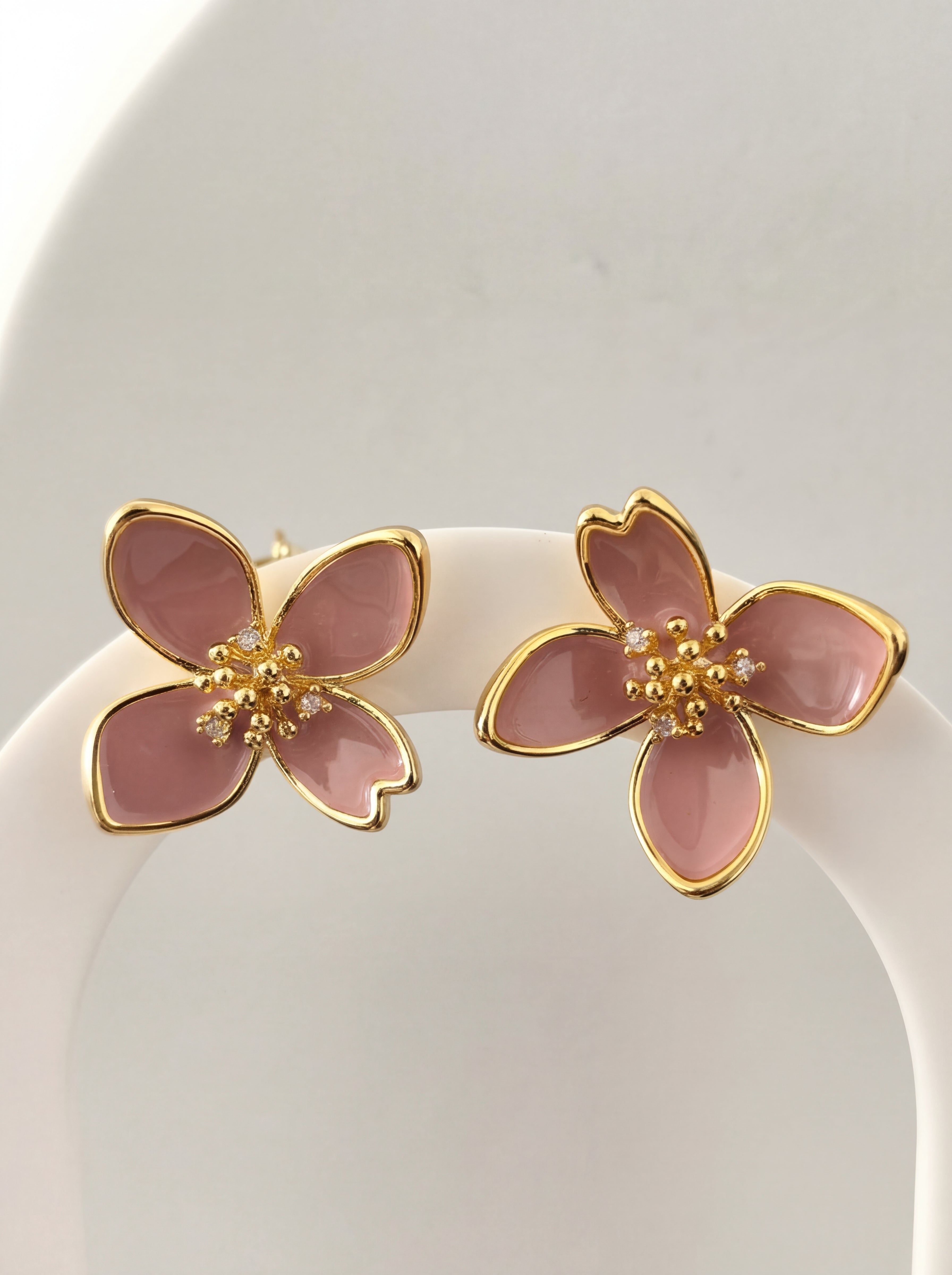 Pink flower-shaped earrings with gold accents on a white background