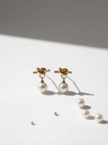 Pair of pearl earrings with gold knots on a light surface