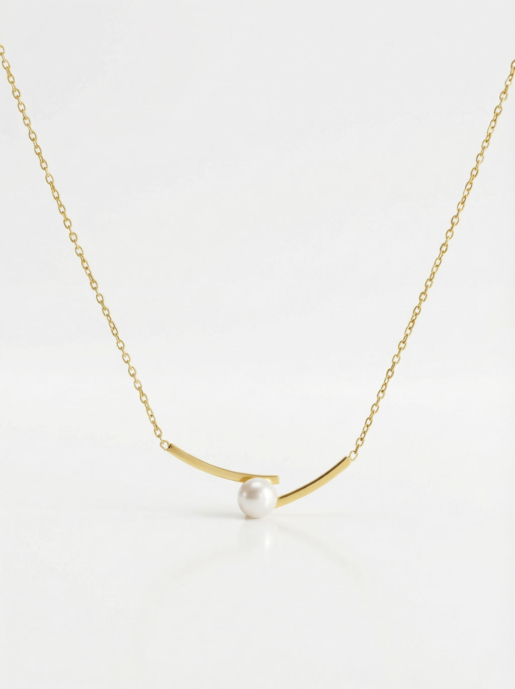Gold necklace with a single pearl on a white background