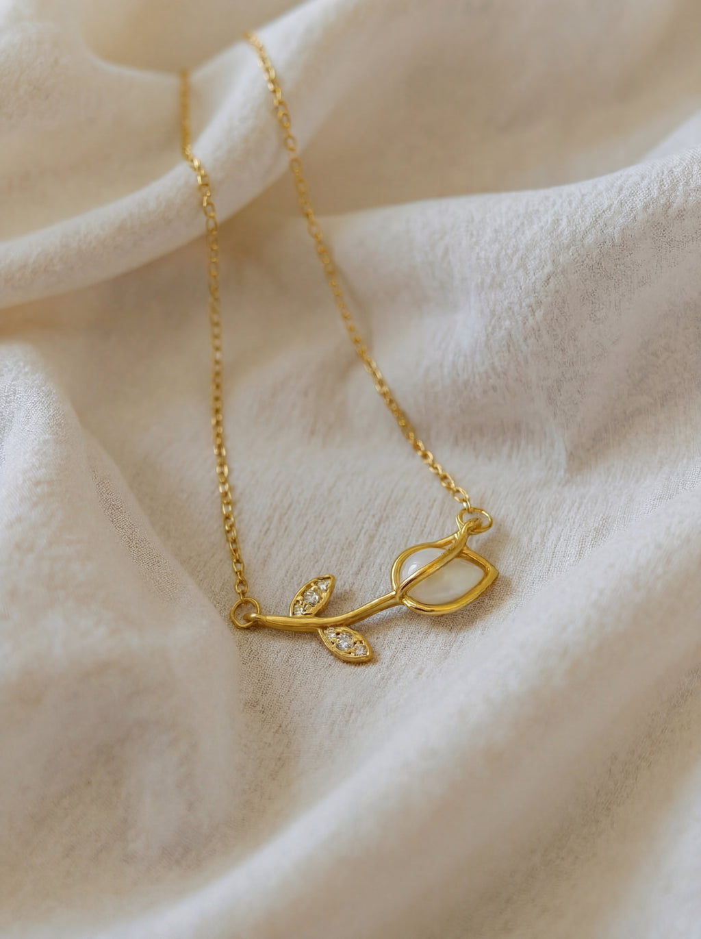 Gold necklace with a delicate design on a soft beige fabric background