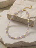 Necklace with purple and gold beads on a stone surface
