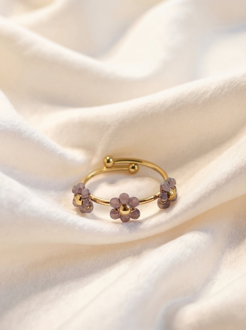 Gold ring with purple gemstones on a soft white fabric background