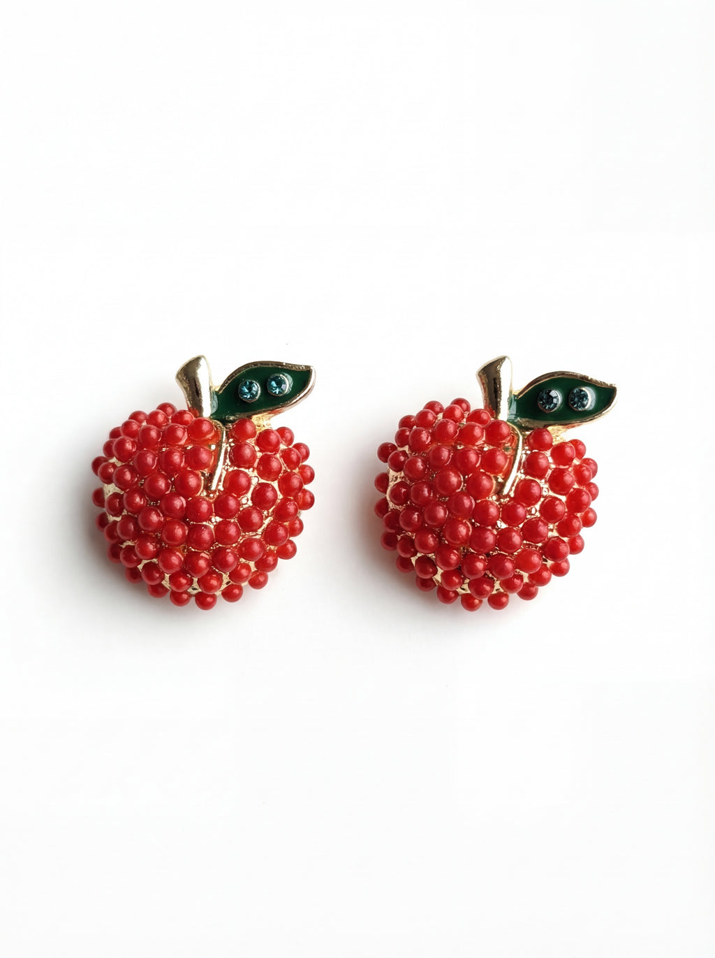 Red beaded apple earrings with gold stems and green leaves on a white background