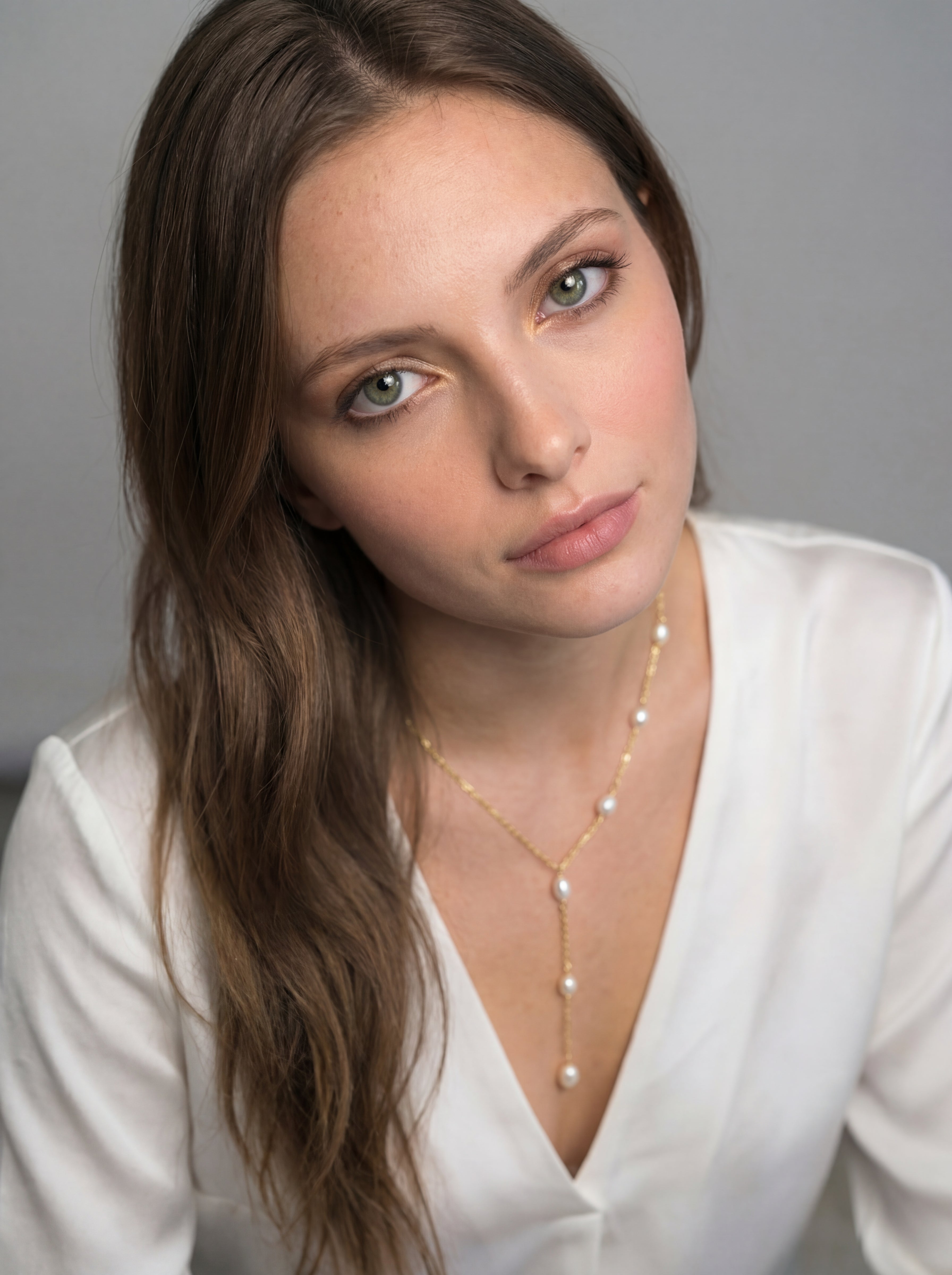 Woman wearing a pearl necklace against a neutral background