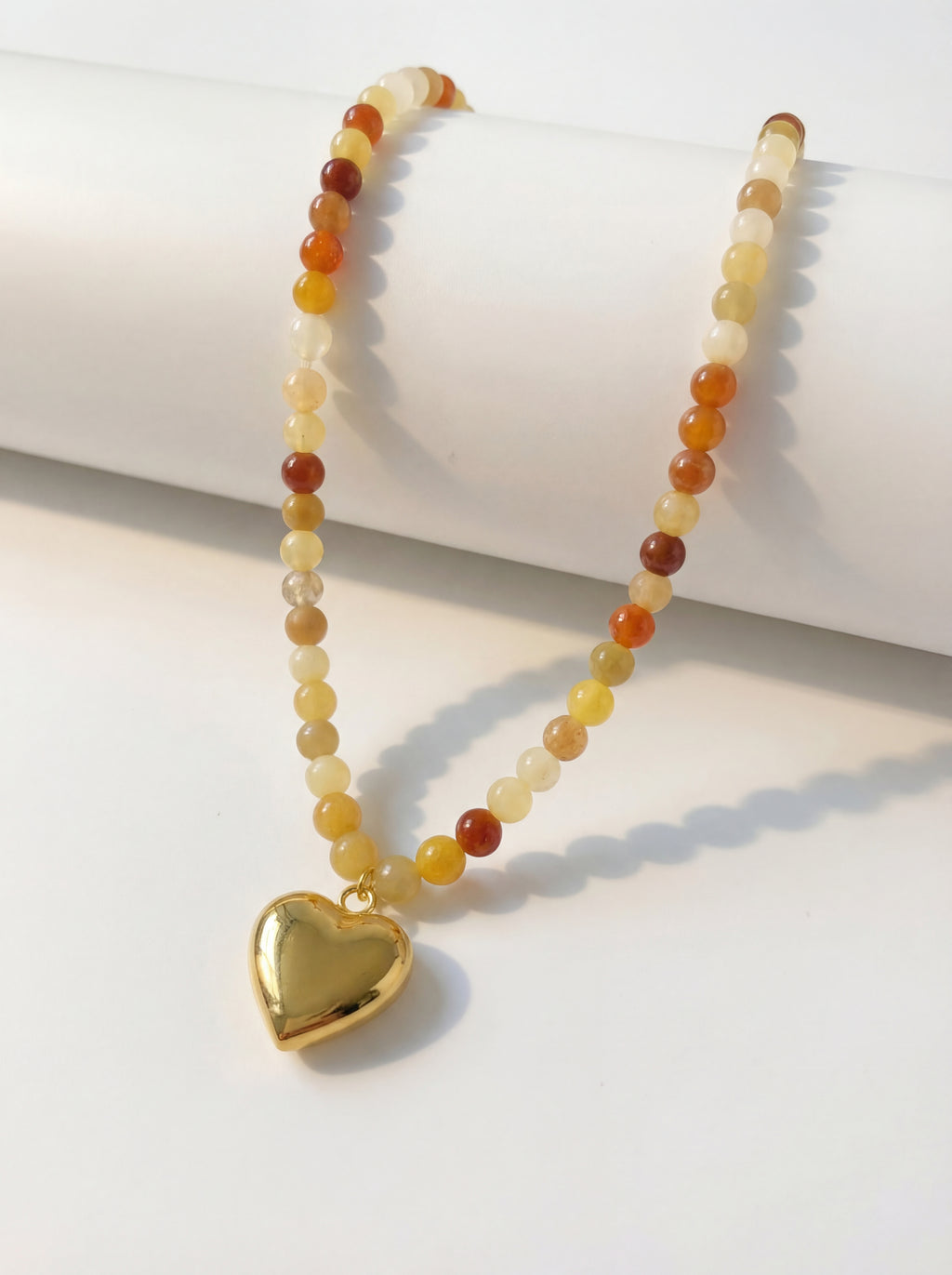 Necklace with heart pendant and multicolored beads on a white surface