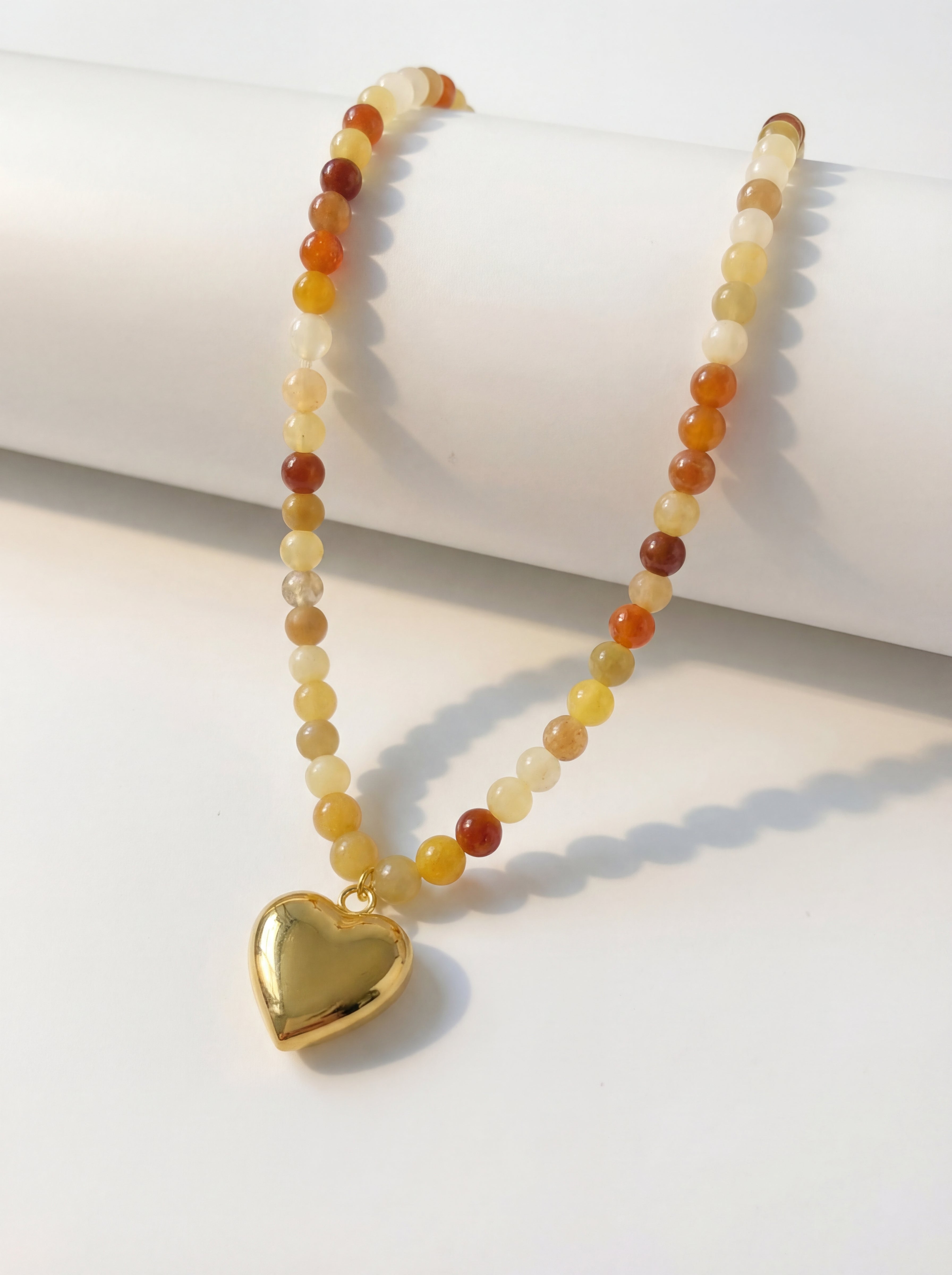 Necklace with heart pendant and multicolored beads on a white surface