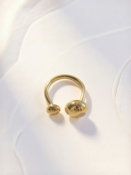 Gold ring with a unique design on a white fabric background