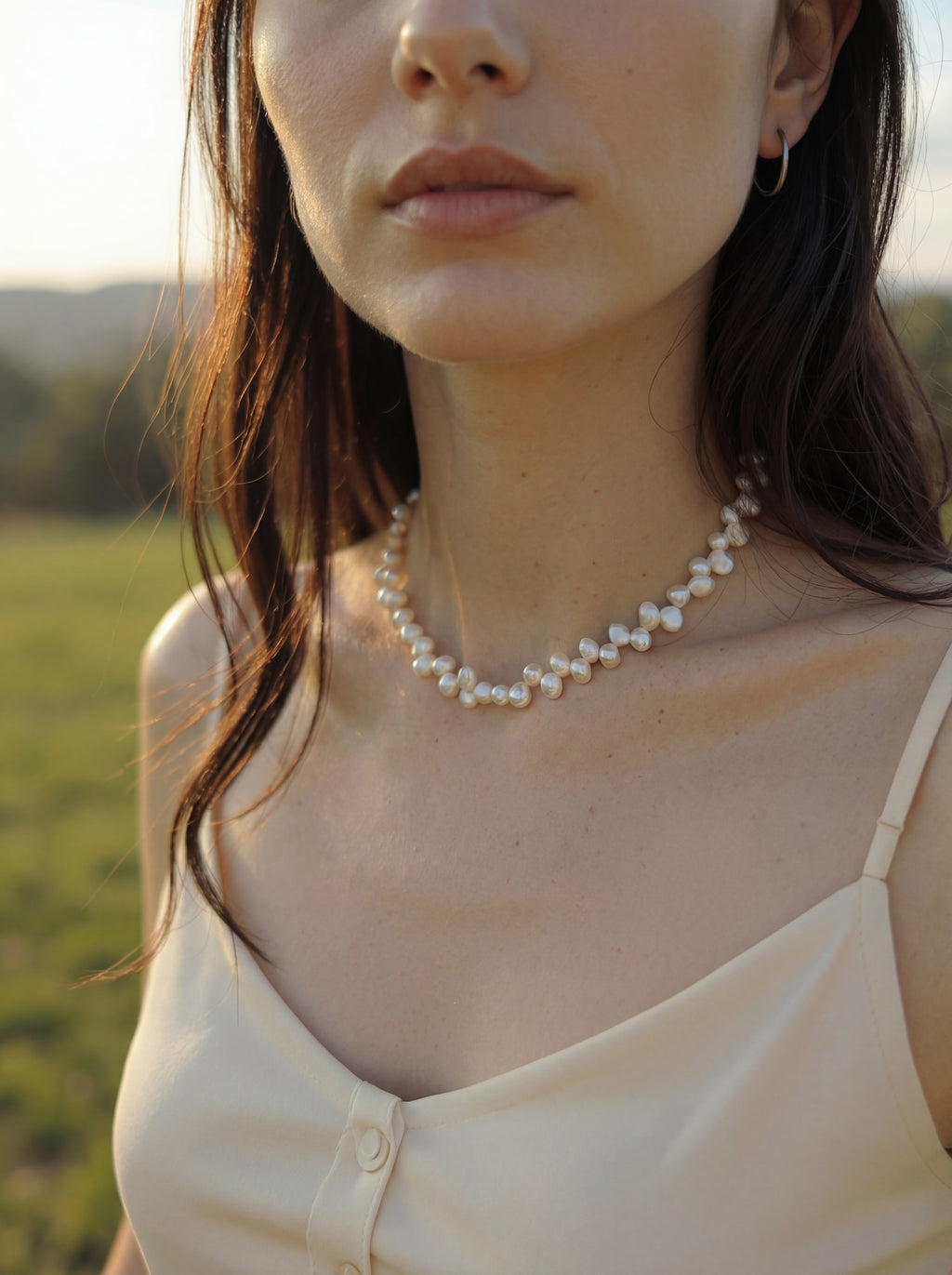 Woman wearing a pearl necklace in a natural setting