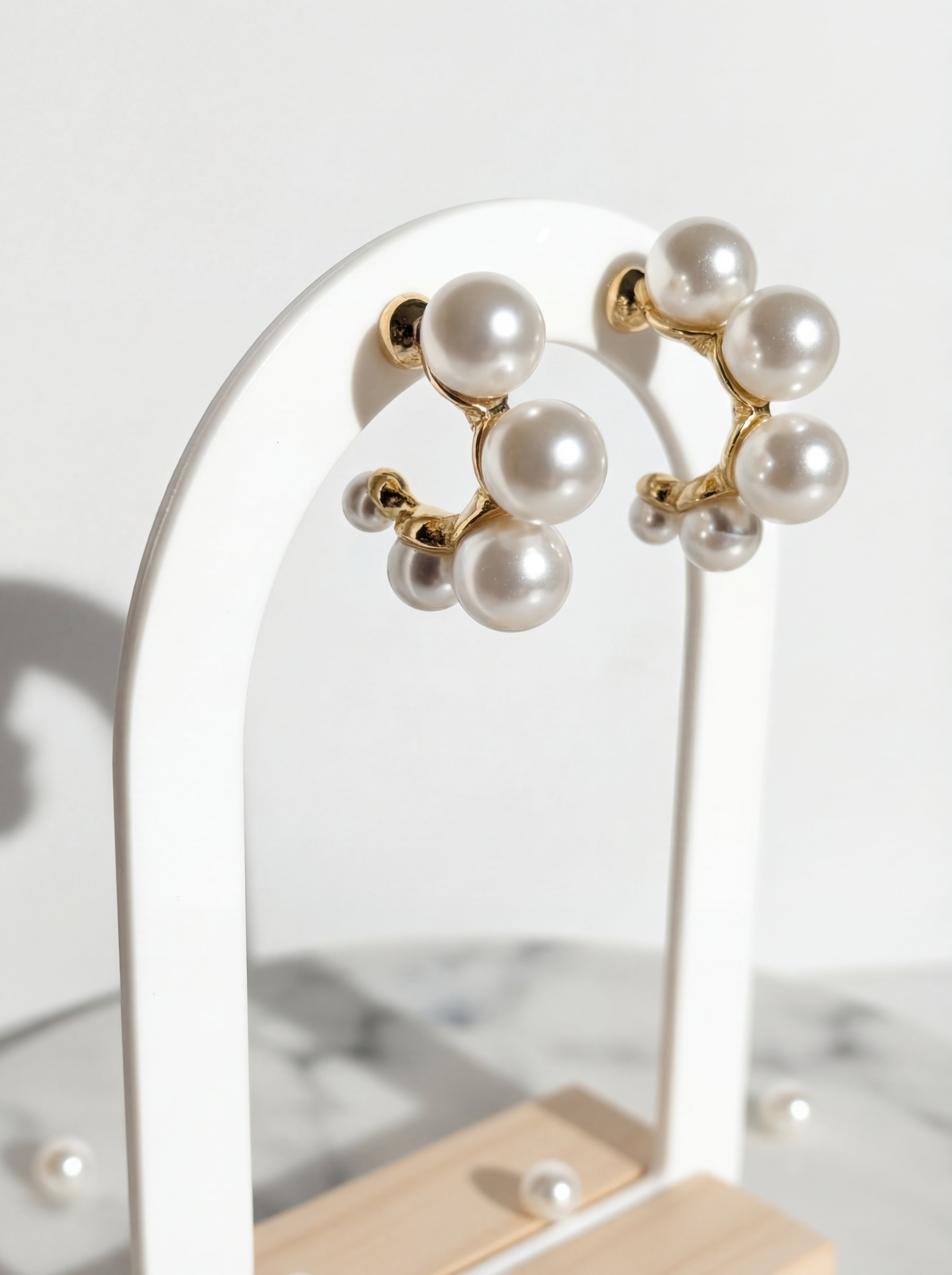 Pearl earrings on a stand with a neutral background