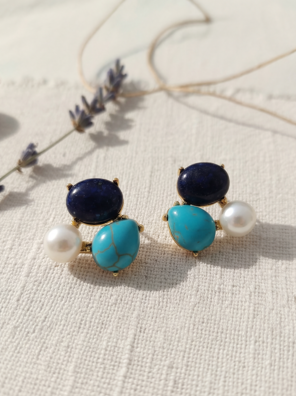 Pair of earrings with blue and turquoise stones on a textured surface
