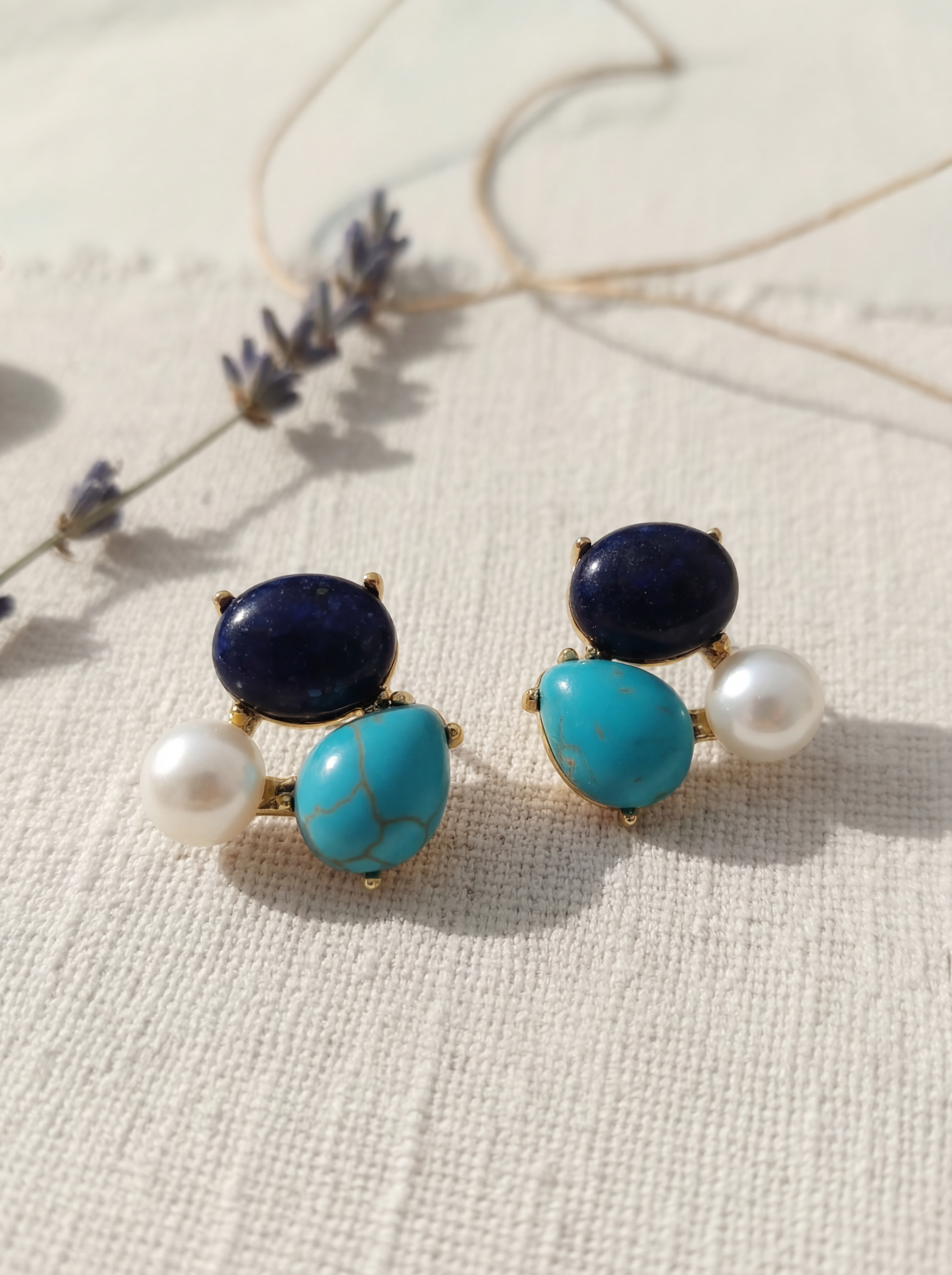 Pair of earrings with blue and turquoise stones on a textured surface