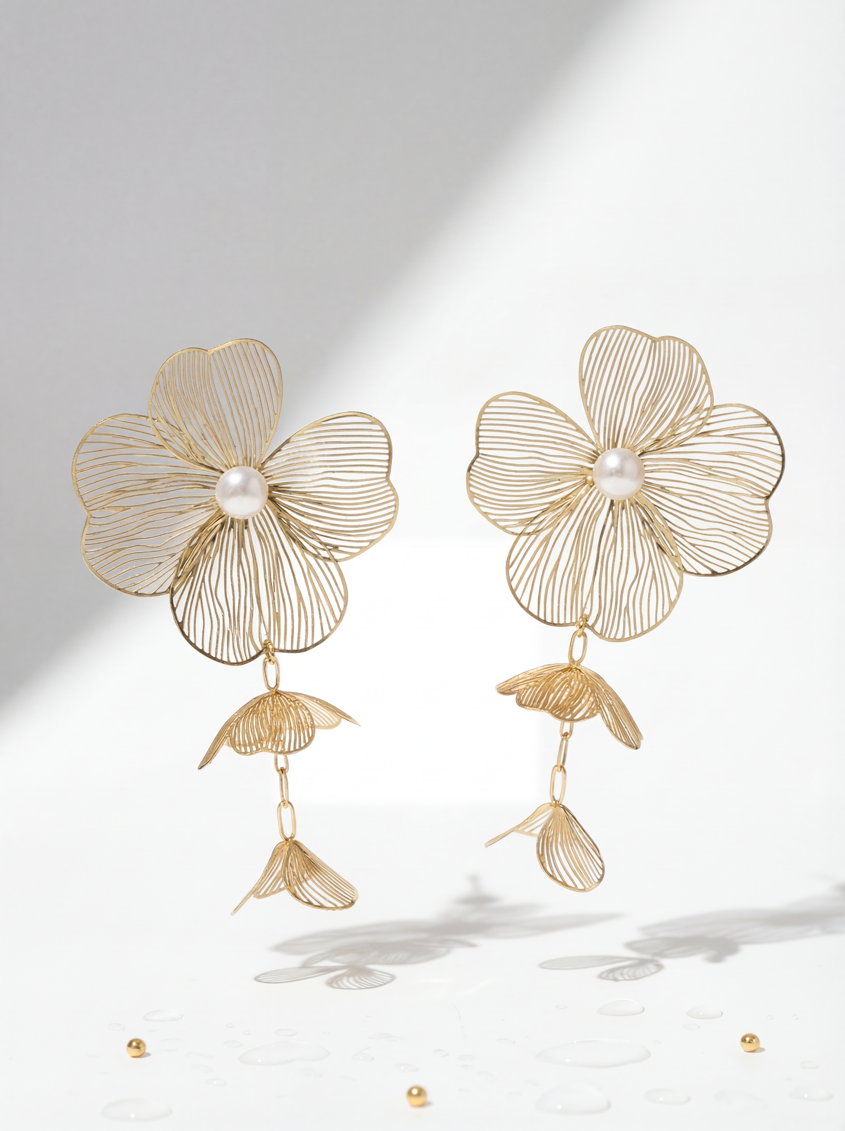 Gold floral earrings with pearl centers on a light gray background