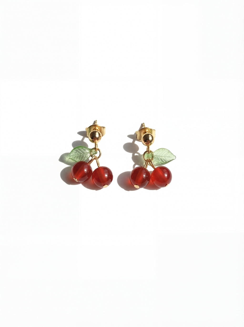 Cherry-themed earrings with red stones and gold accents on a white background