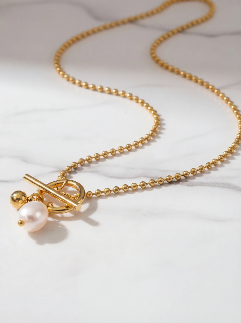 Gold necklace with a pearl pendant on a white background