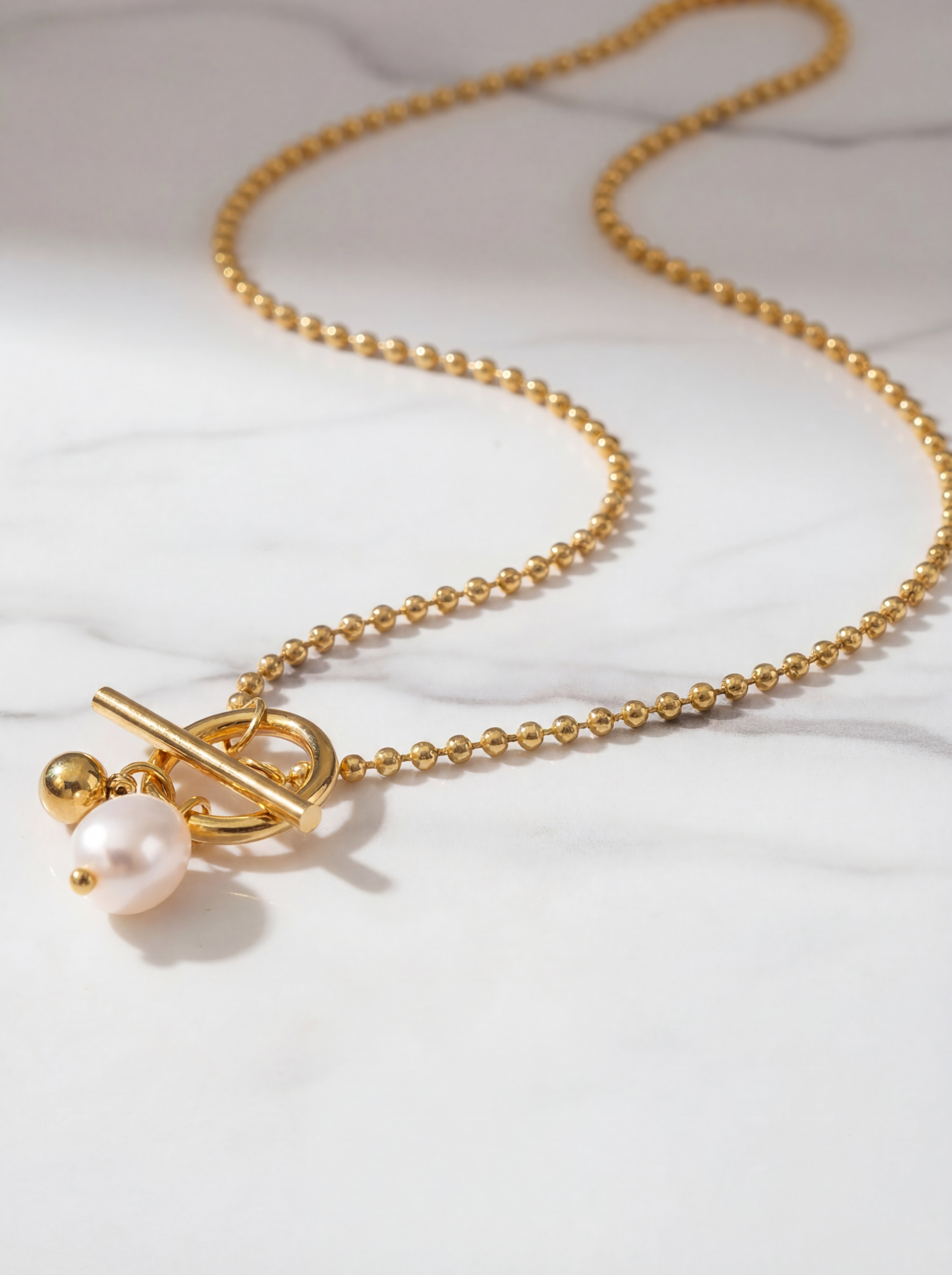 Gold necklace with a pearl pendant on a white background