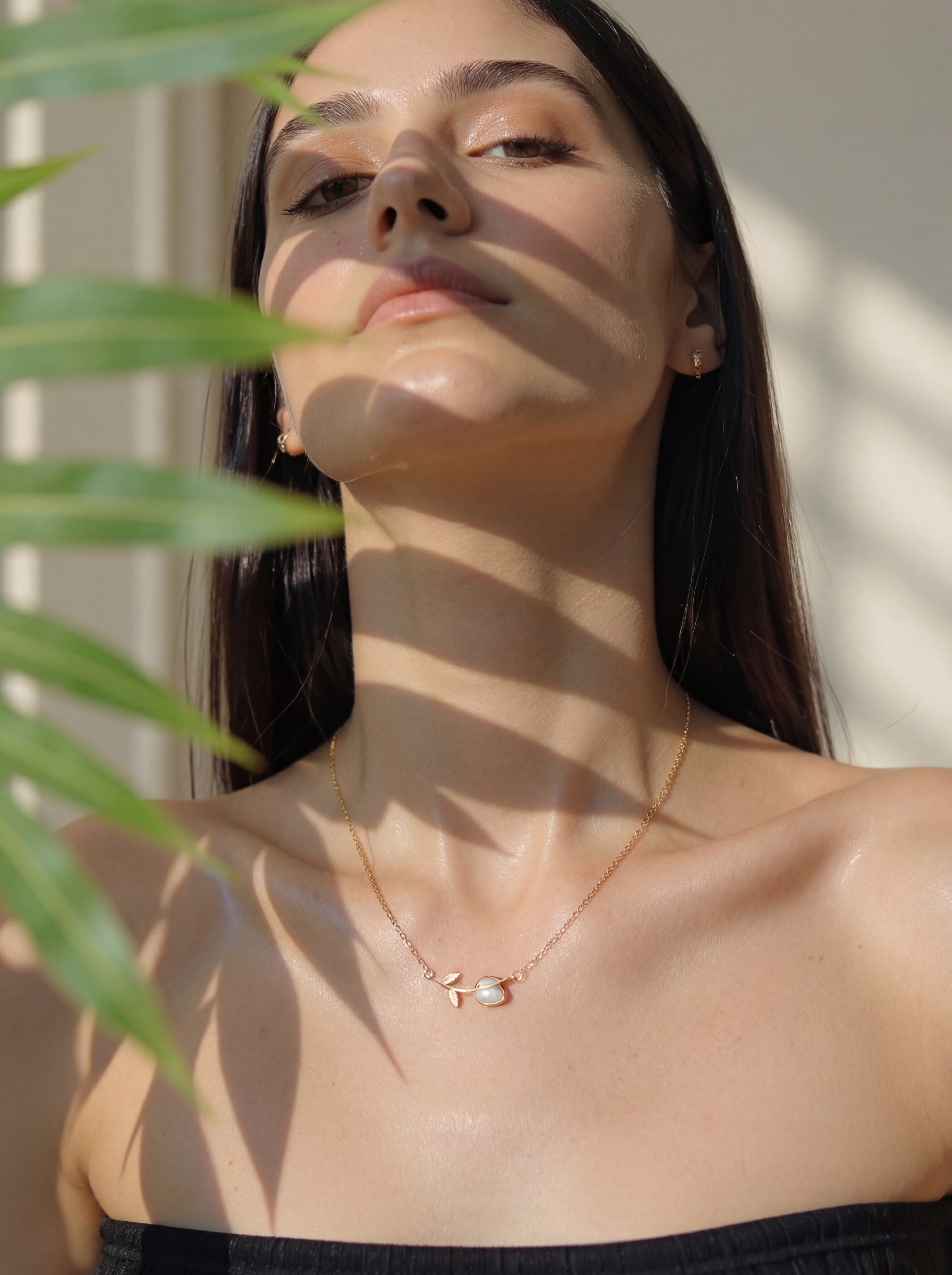 Woman wearing a delicate necklace with a leafy background