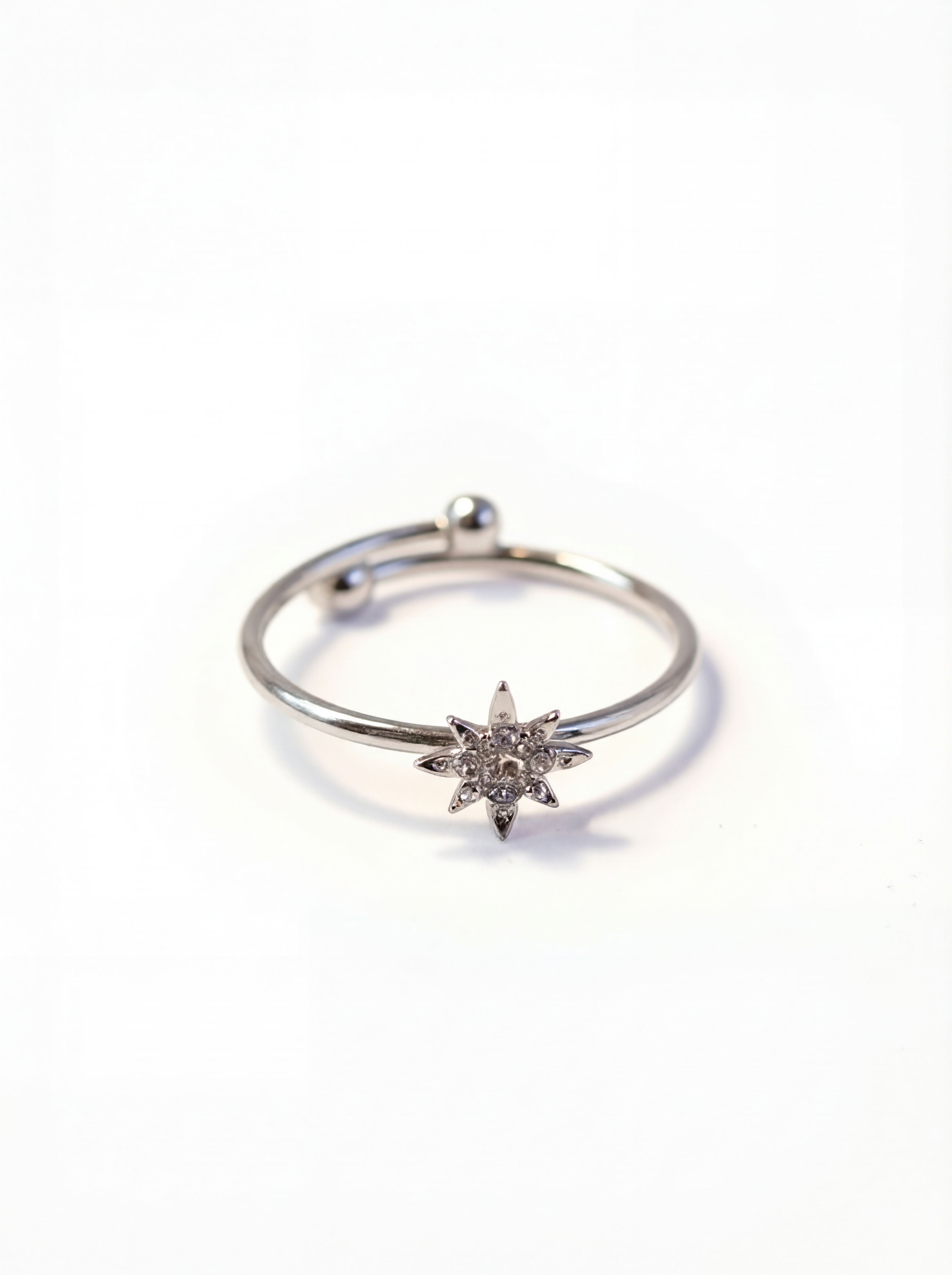 Silver ring with a star-shaped diamond on a white background