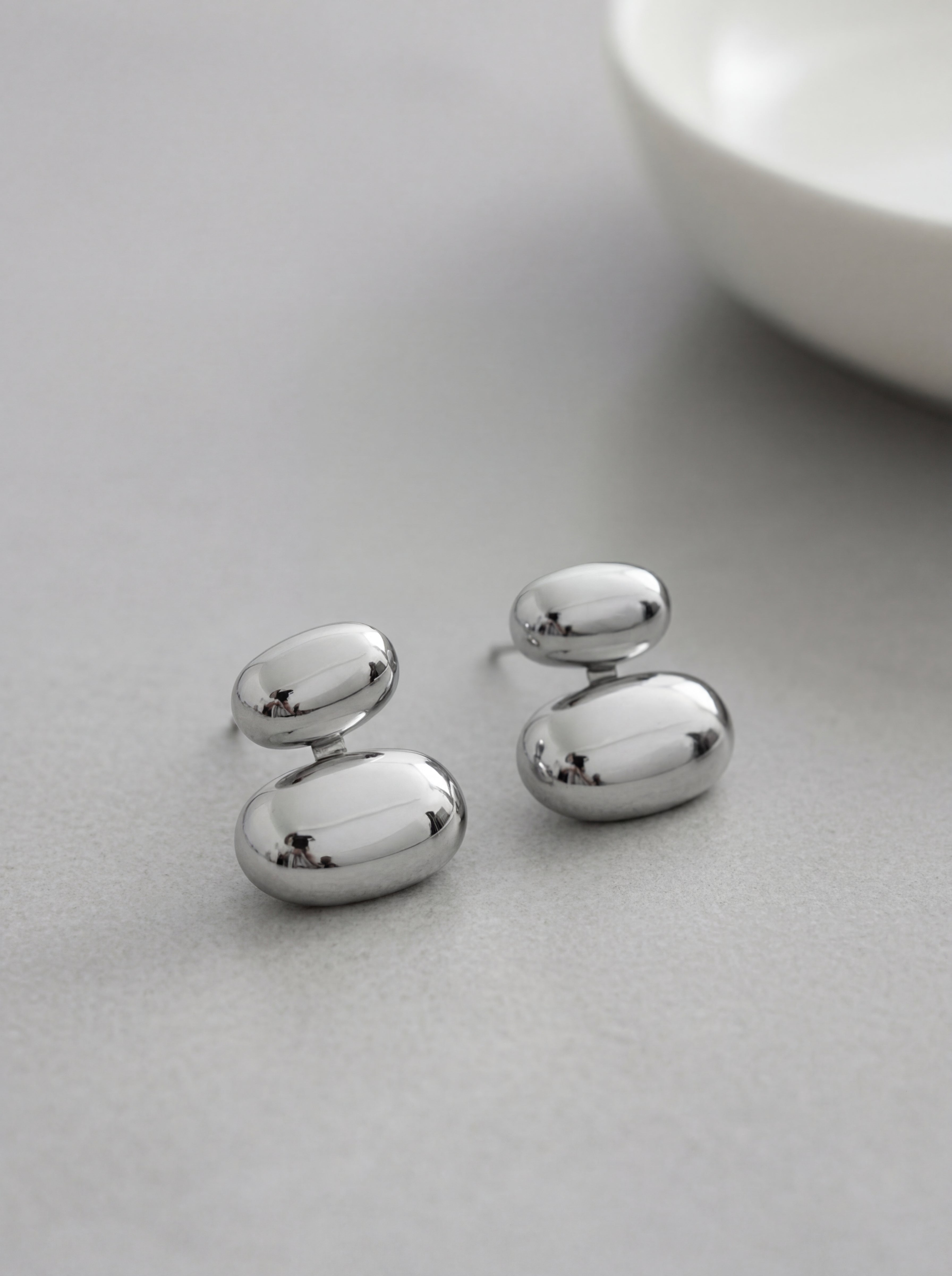 Pair of silver earrings on a light gray surface