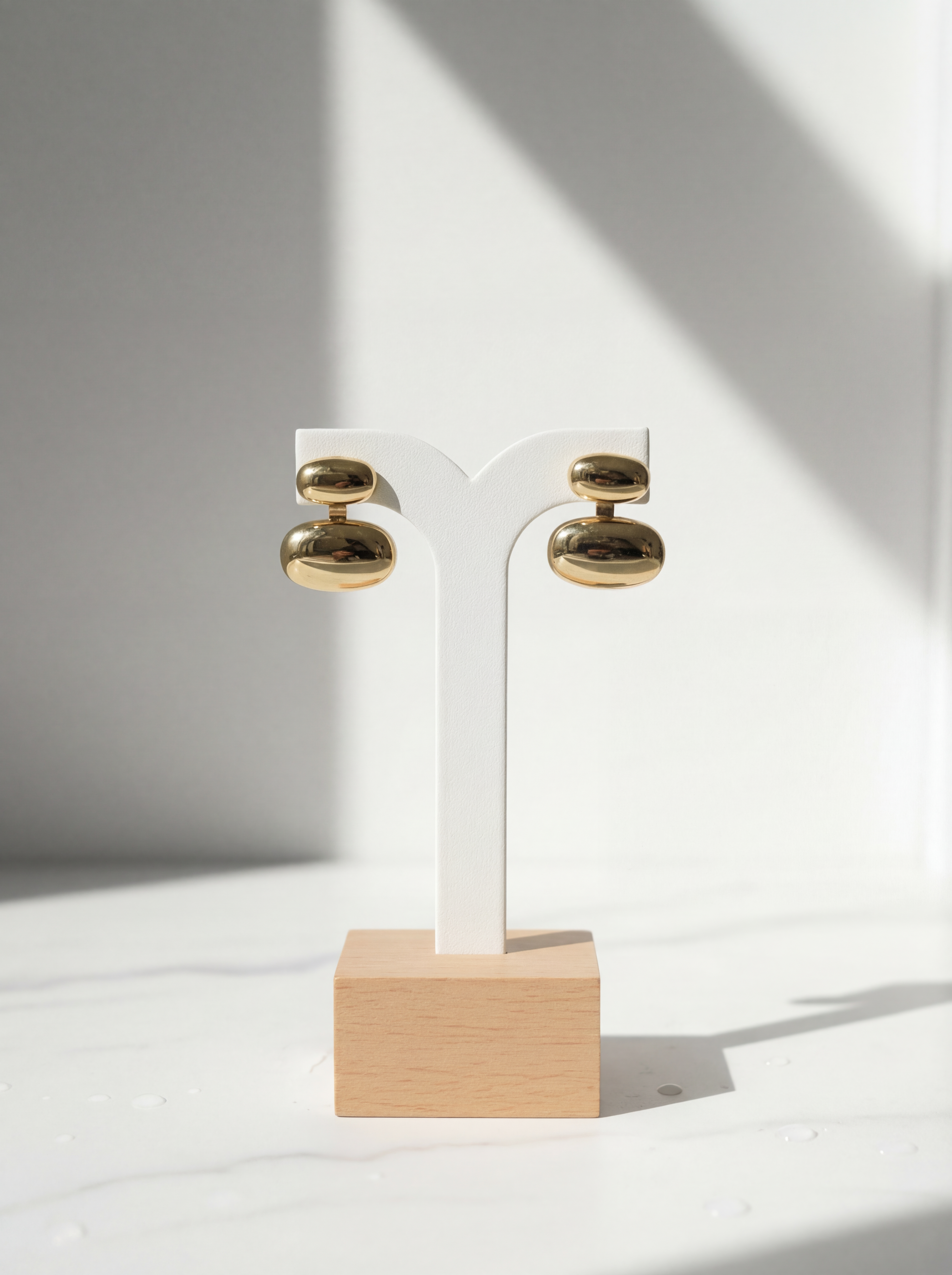 Gold earrings on a wooden stand against a white background