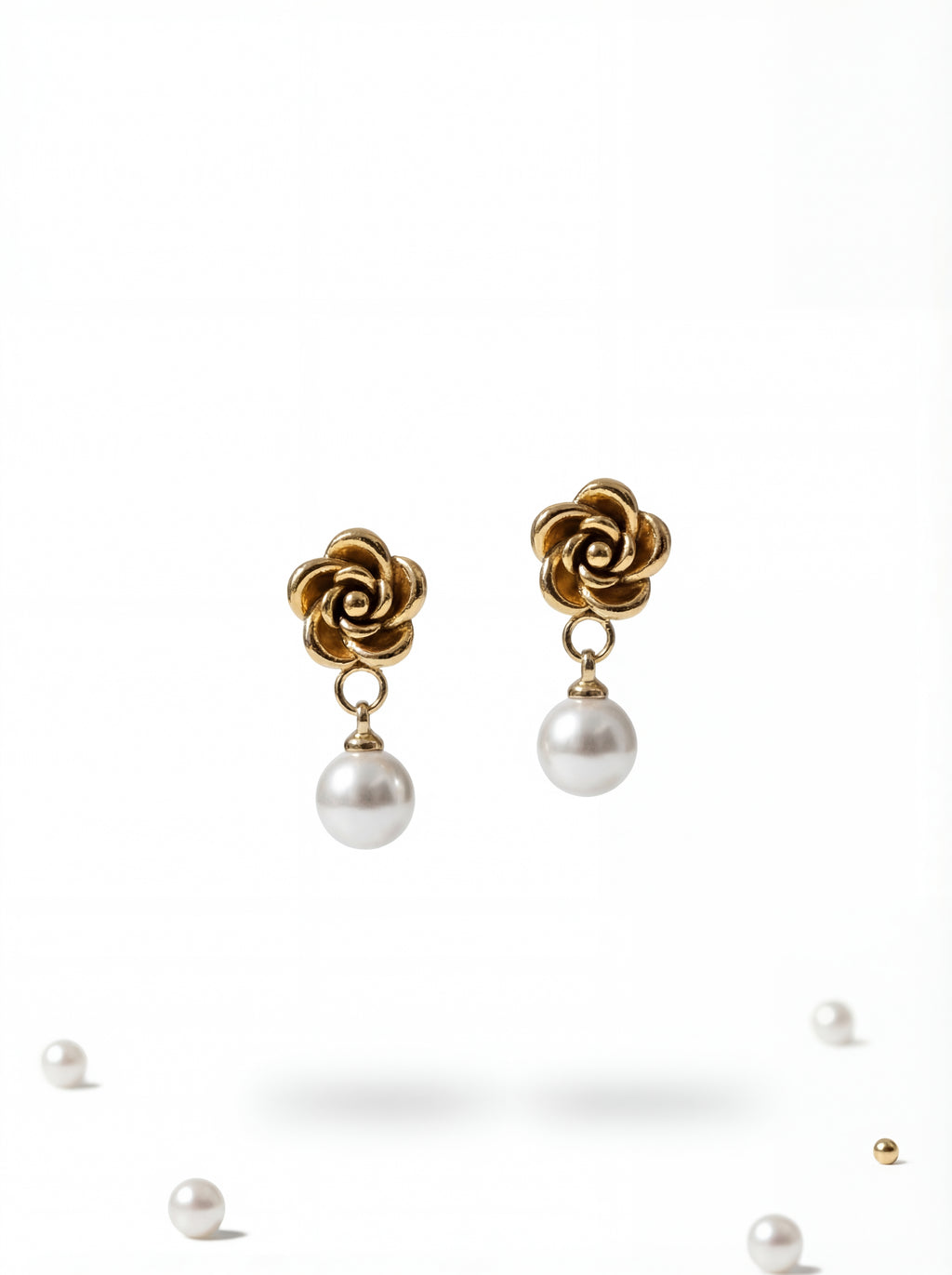 Gold flower-shaped earrings with pearl drops on a white background