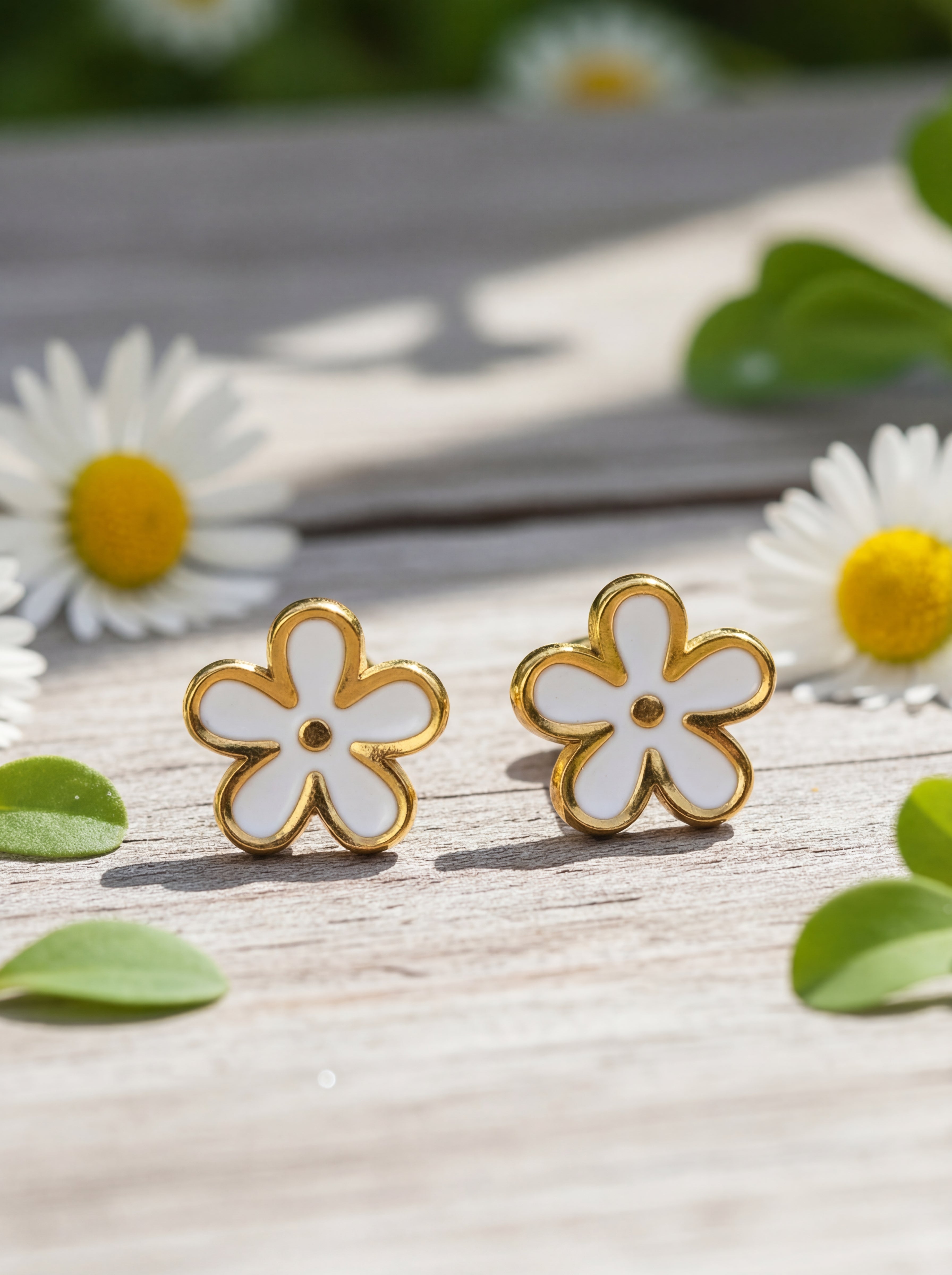 Flower-shaped earrings on a wooden surface with daisies in the background