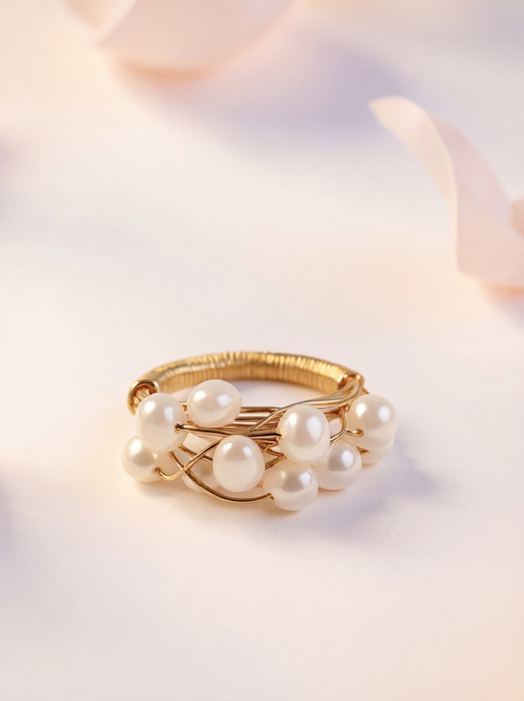 Gold ring with pearls on a soft pink background