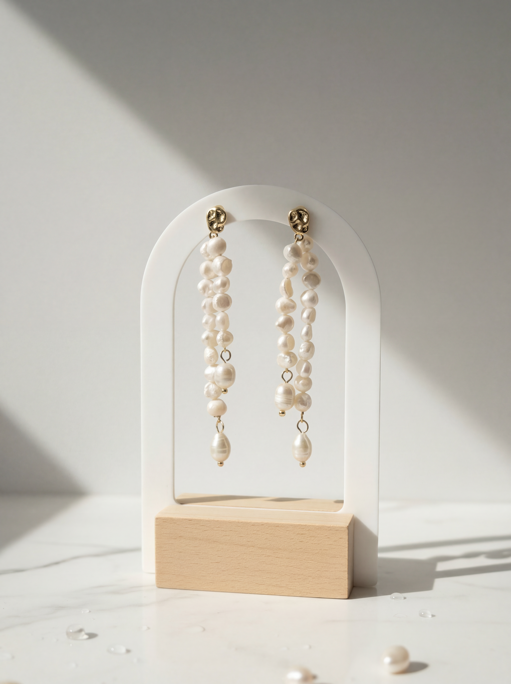 Pearl earrings on a white arch stand with a light background