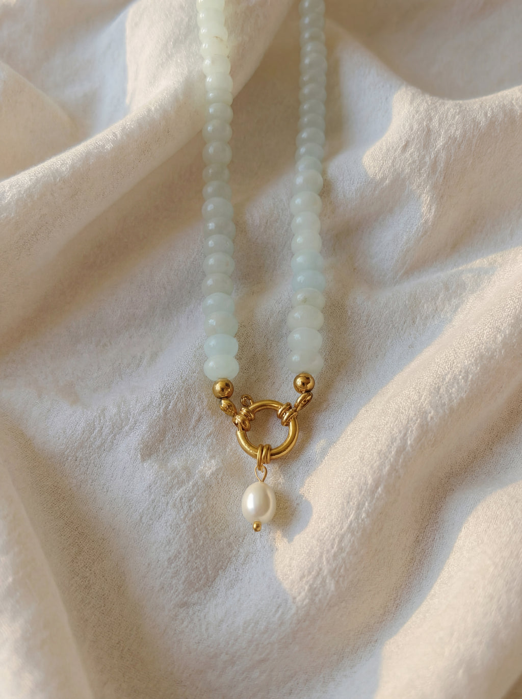 Pearl necklace with a gold clasp on a soft beige fabric background