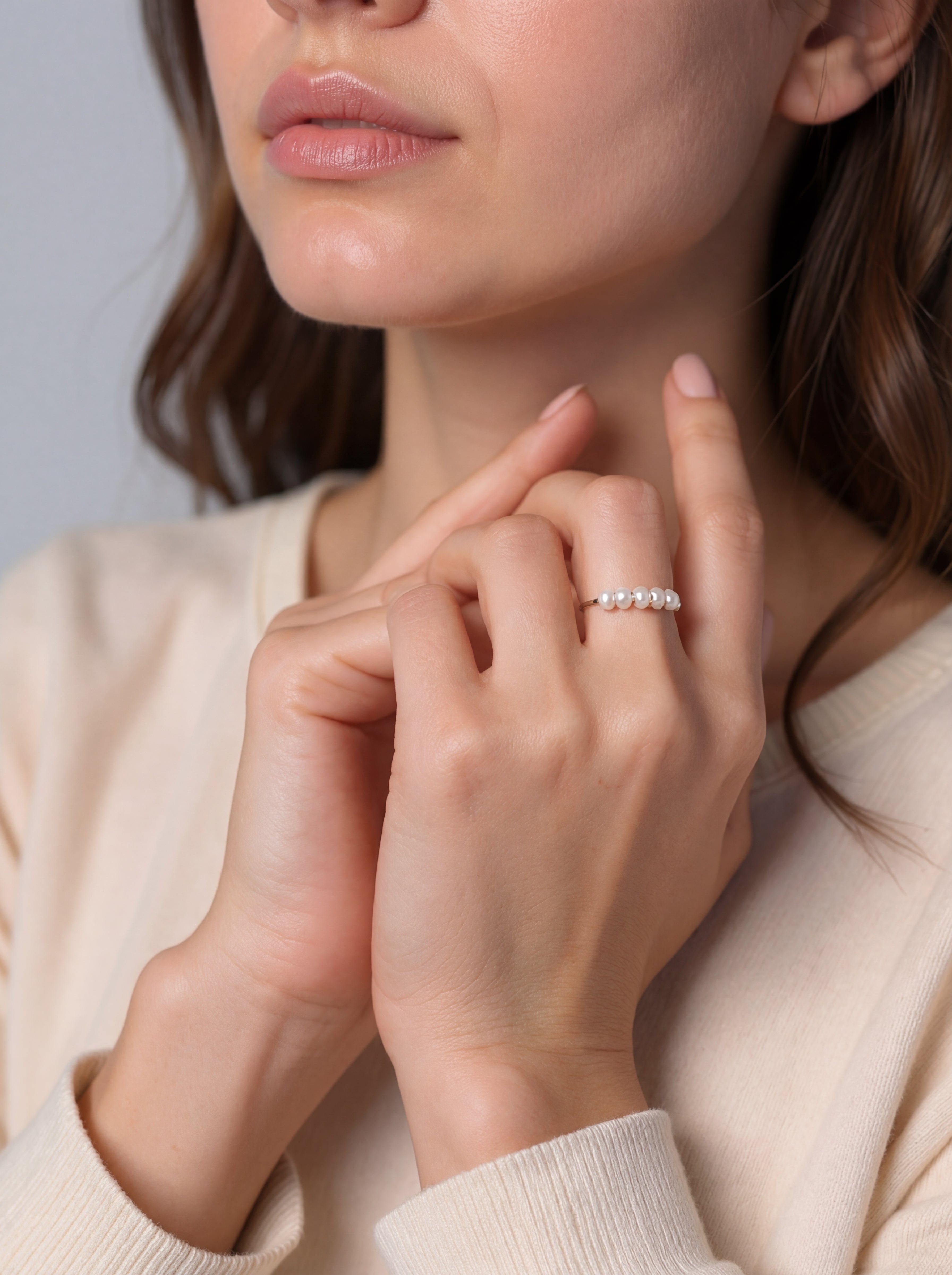 Close-up of a woman wearing a silver ring on her finger against a neutral background