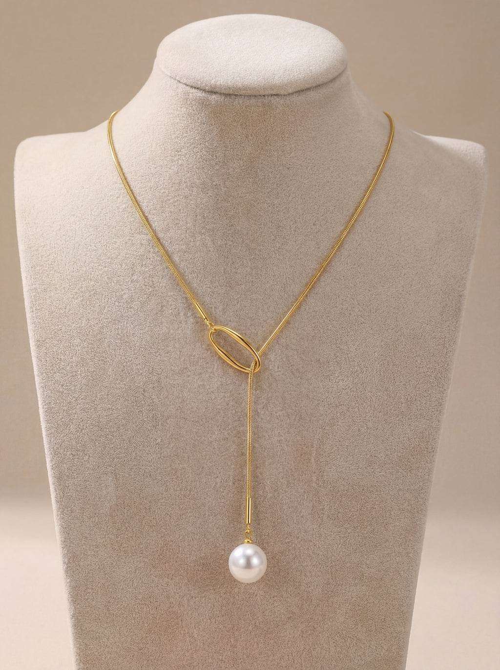 Gold necklace with a pearl pendant on a mannequin bust.
