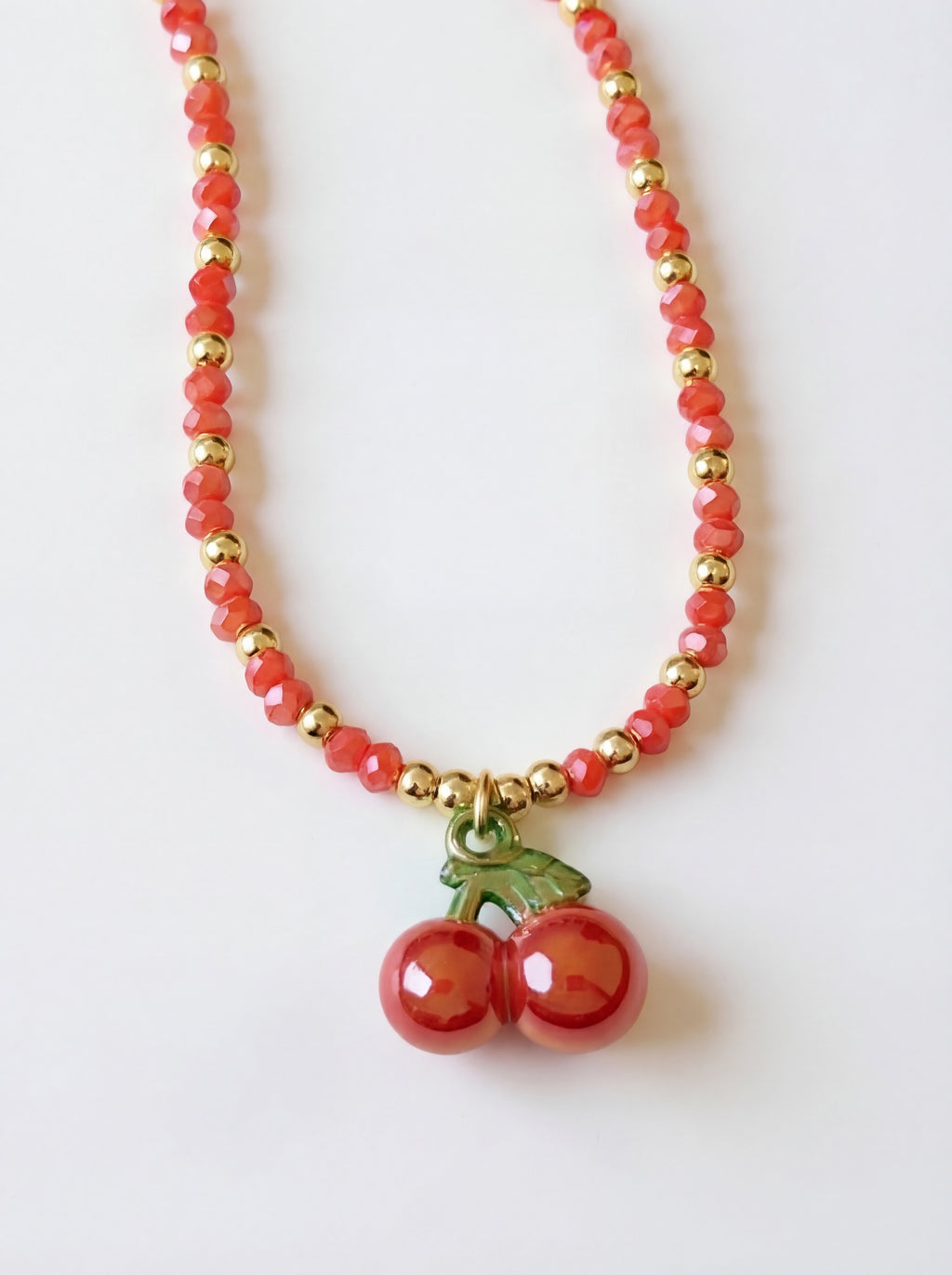 Necklace with red beads and cherry charm on a white background