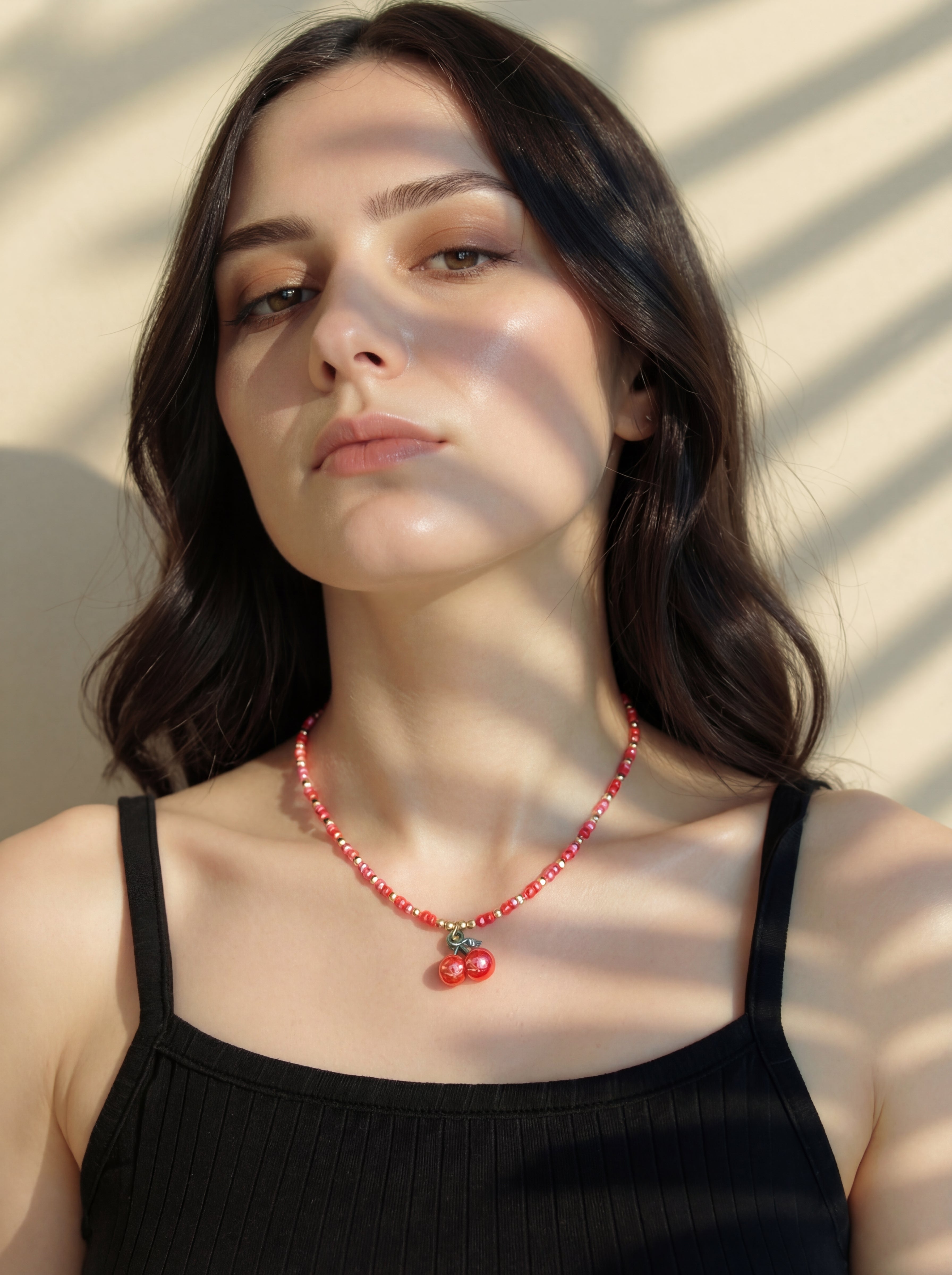 Woman wearing a red beaded necklace with a neutral background