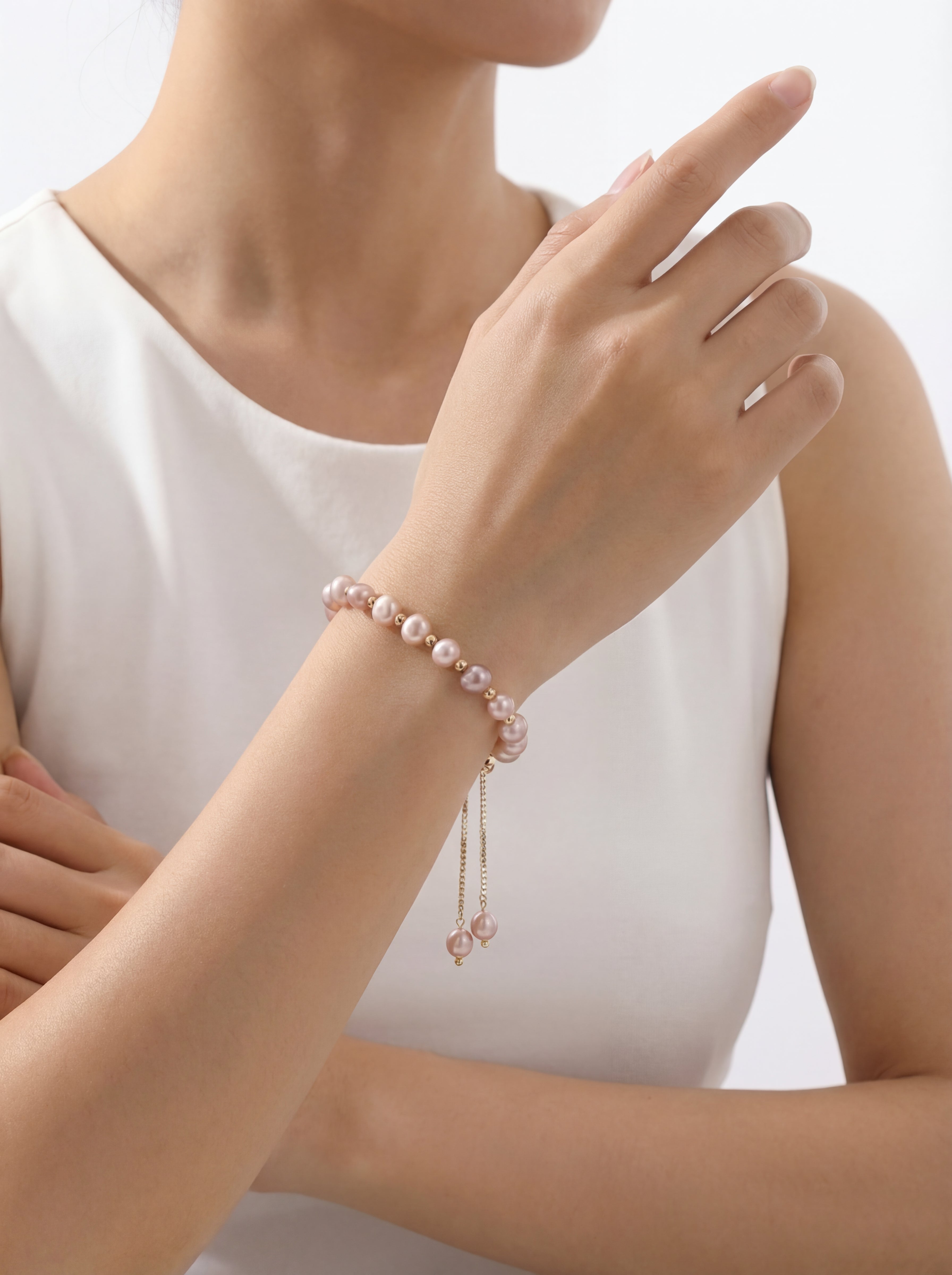 Woman wearing a pink pearl bracelet on a plain background