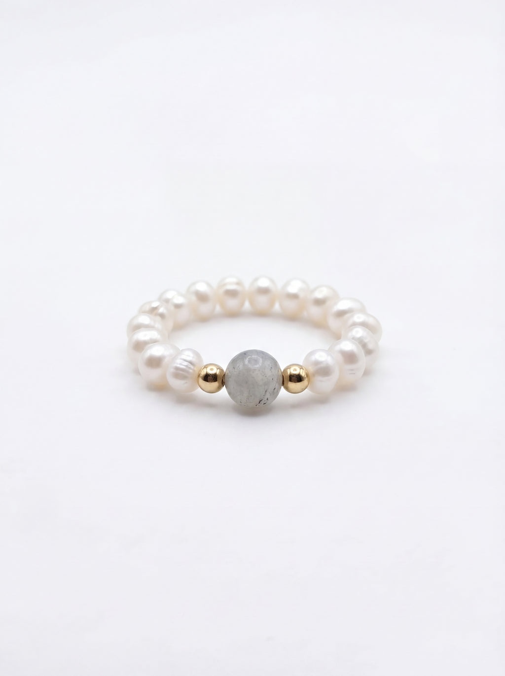 Pearl ring with gold and gray beads on a white background