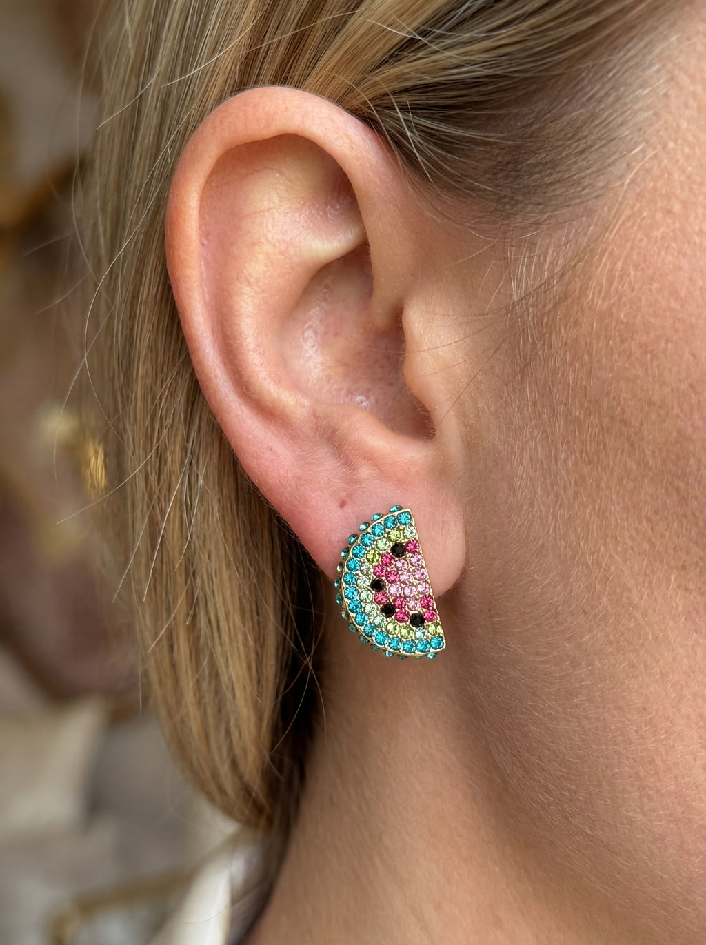 Close-up of an ear wearing a colorful earring with a blurred background